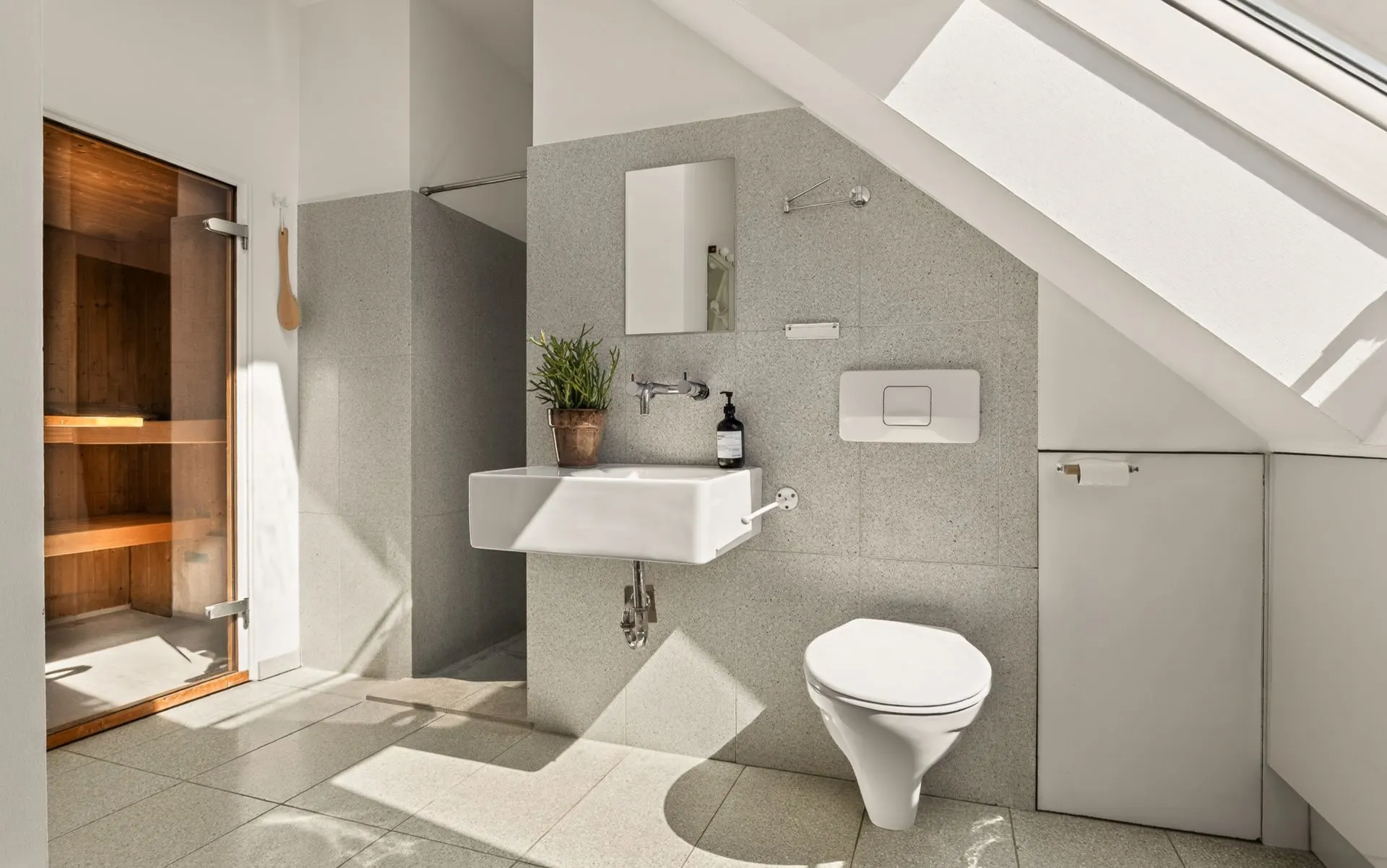 Modernes Badezimmer mit Waschbecken, Spiegel, WC, großer Fensterfront und Sauna.