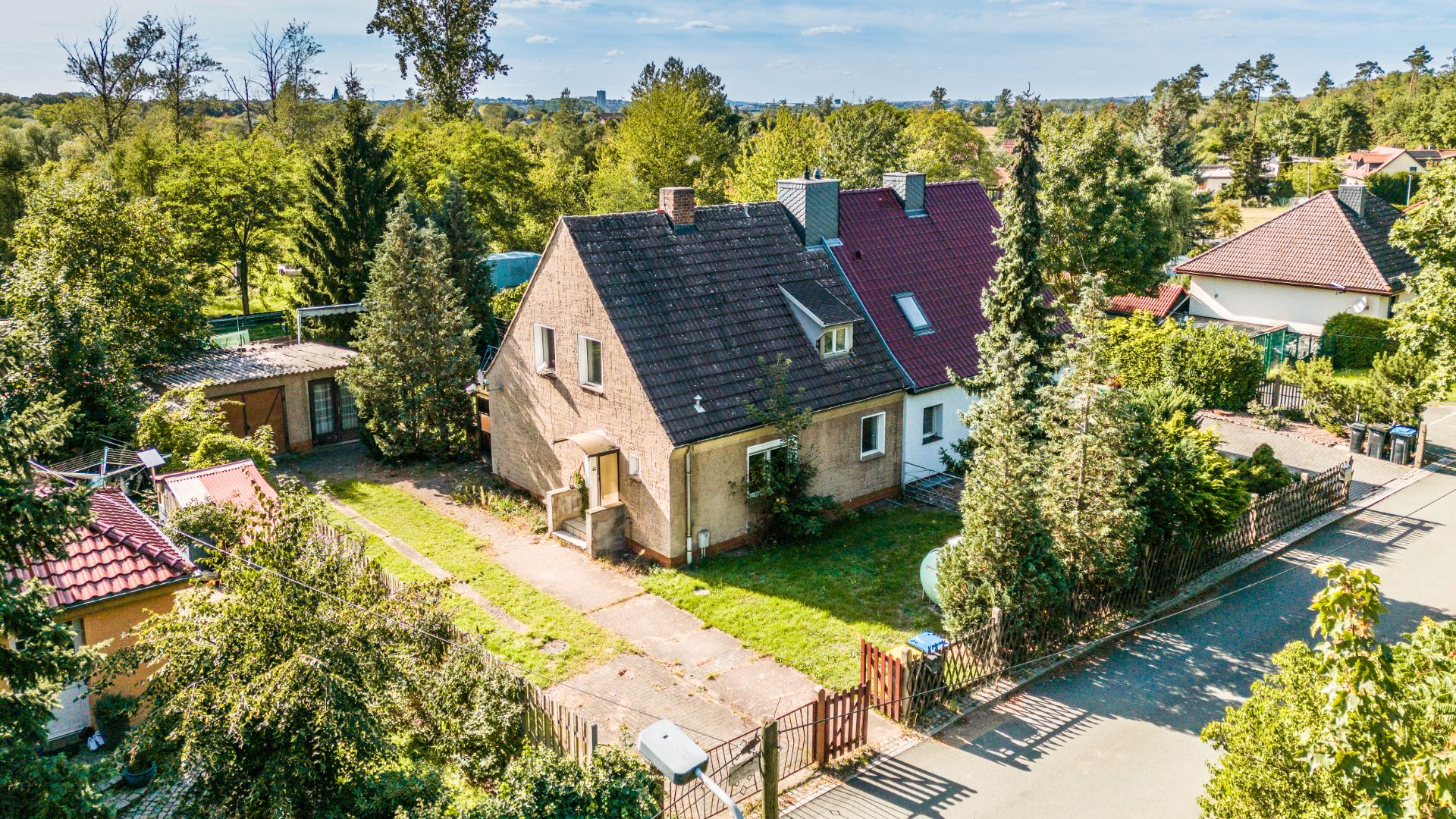 Zweistöckiges Einfamilienhaus mit Garten, Auffahrt und umgeben von Bäumen in einer ruhigen Wohngegend.