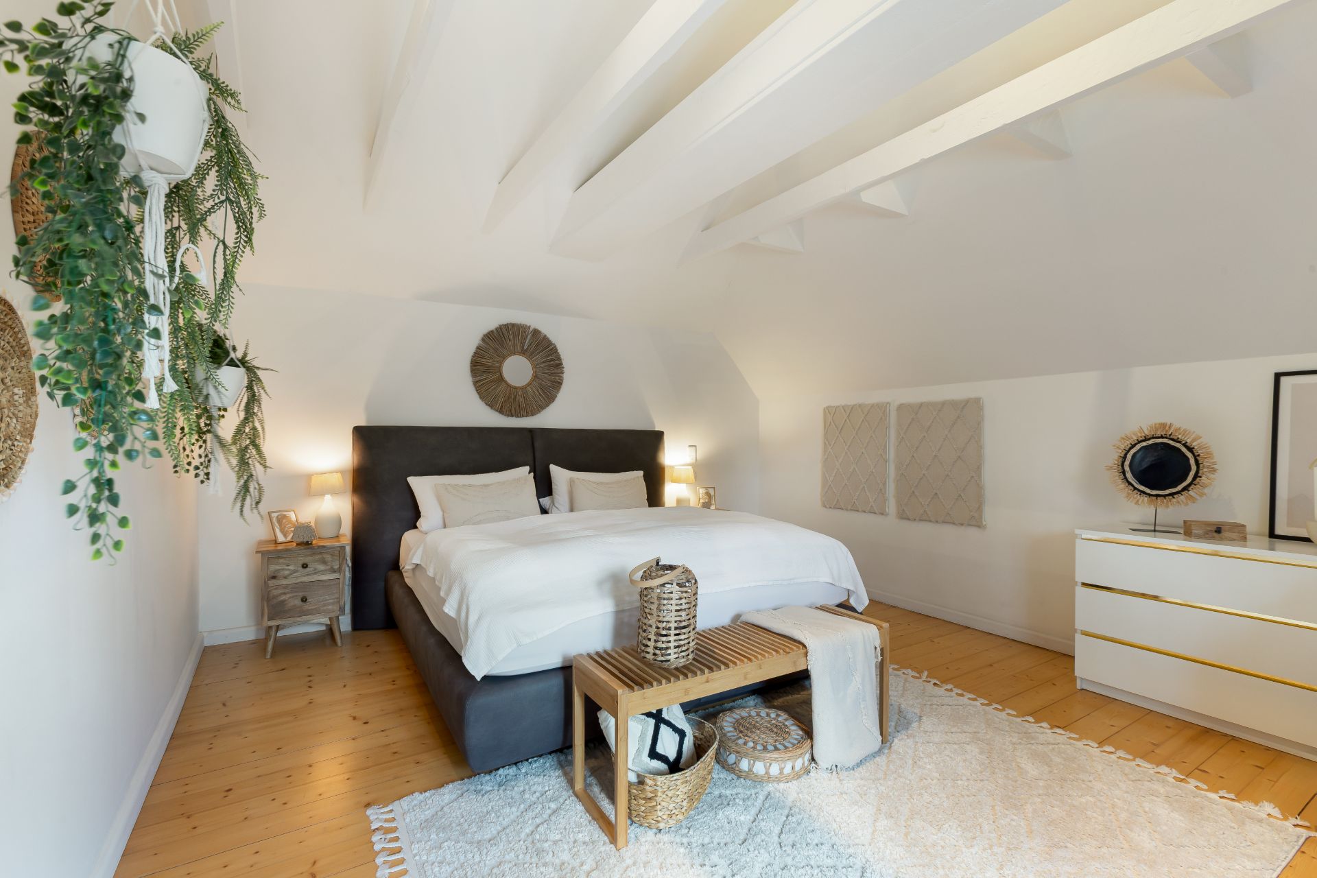 Helles Schlafzimmer mit Doppelbett, Holzboden, Pflanzen und Kommode, dekorativ eingerichtet.