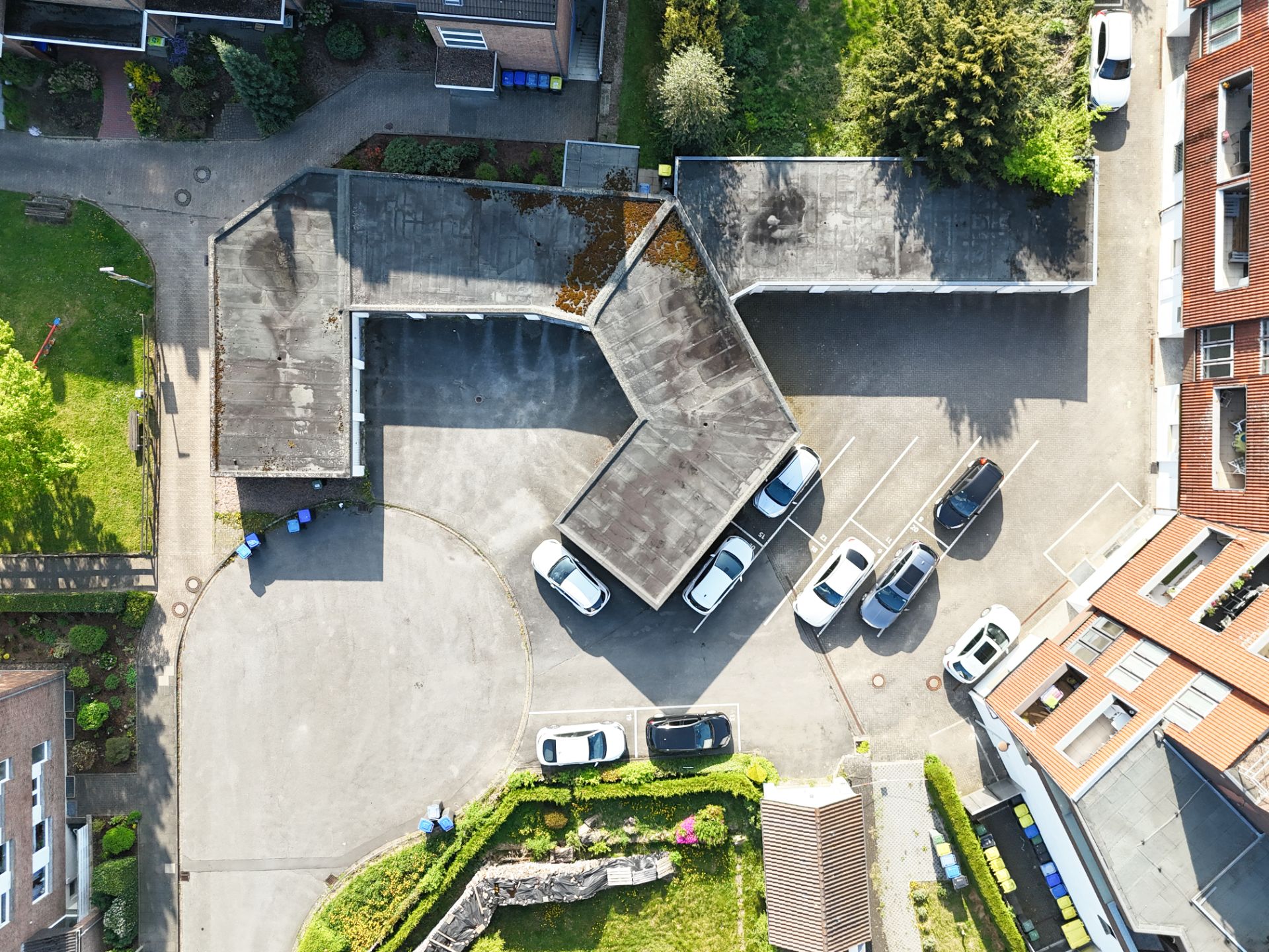 Luftaufnahme eines Wohnhofs mit mehreren Autos auf Parkplätzen und umgebenen Gebäuden.