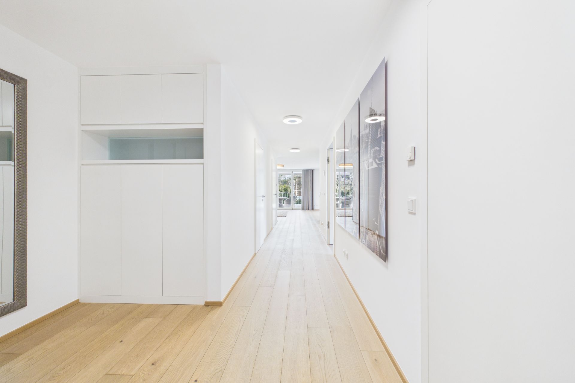 Heller Flur mit Holzfußboden, Einbauschrank und großem Wandspiegel in einer Wohnung.