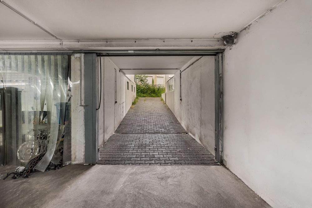 Blick aus einer Garage auf eine gepflasterte Ausfahrt ins Freie.