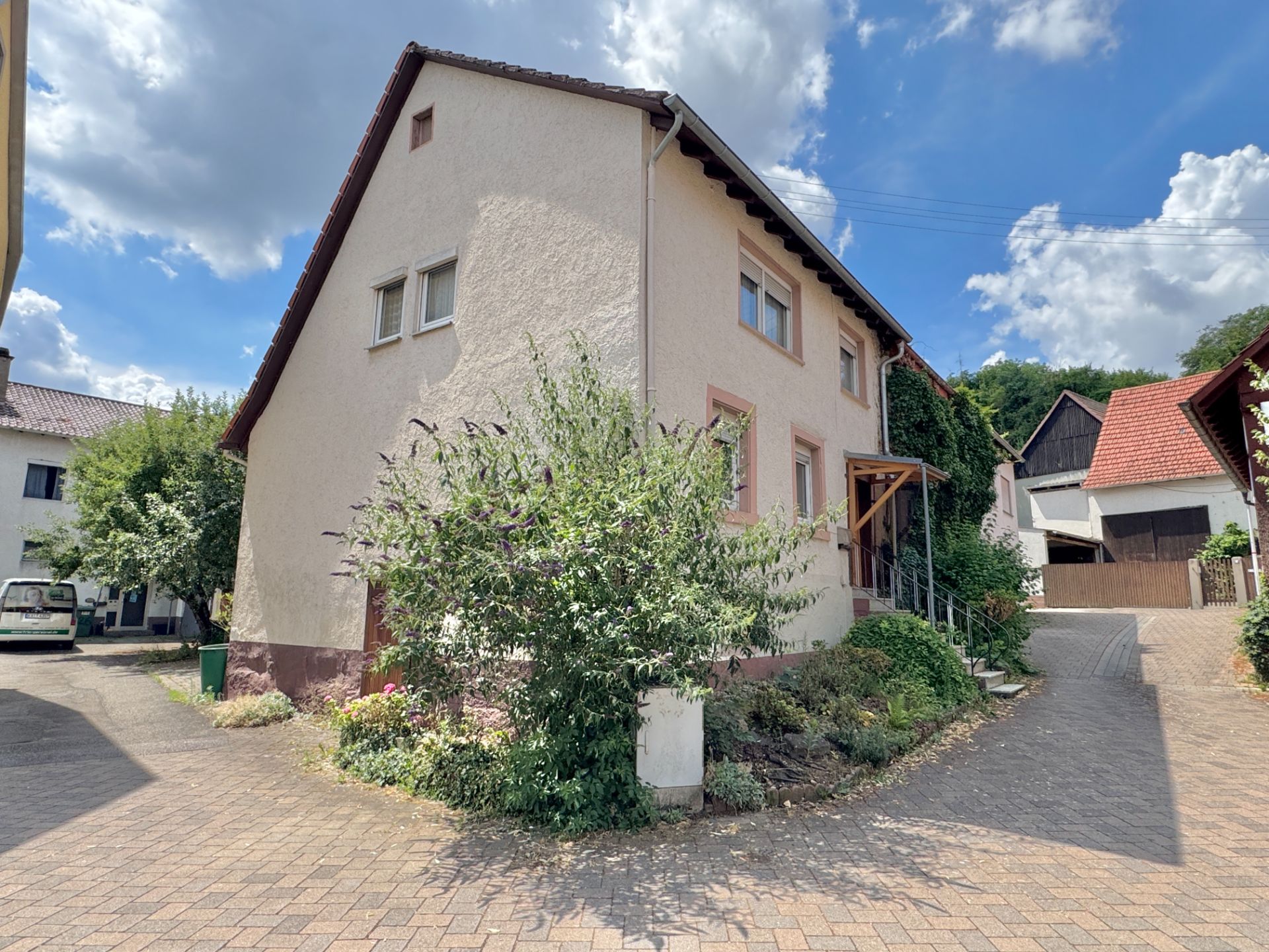 Zweistöckiges Wohnhaus mit hellem Putz und Vorgarten in einer ruhigen Wohnstraße.