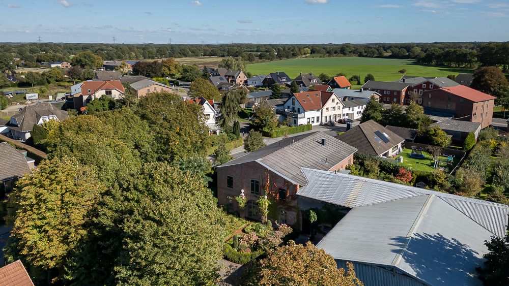 Luftaufnahme eines Wohngebiets mit Häusern, Gärten und umliegenden Feldern.