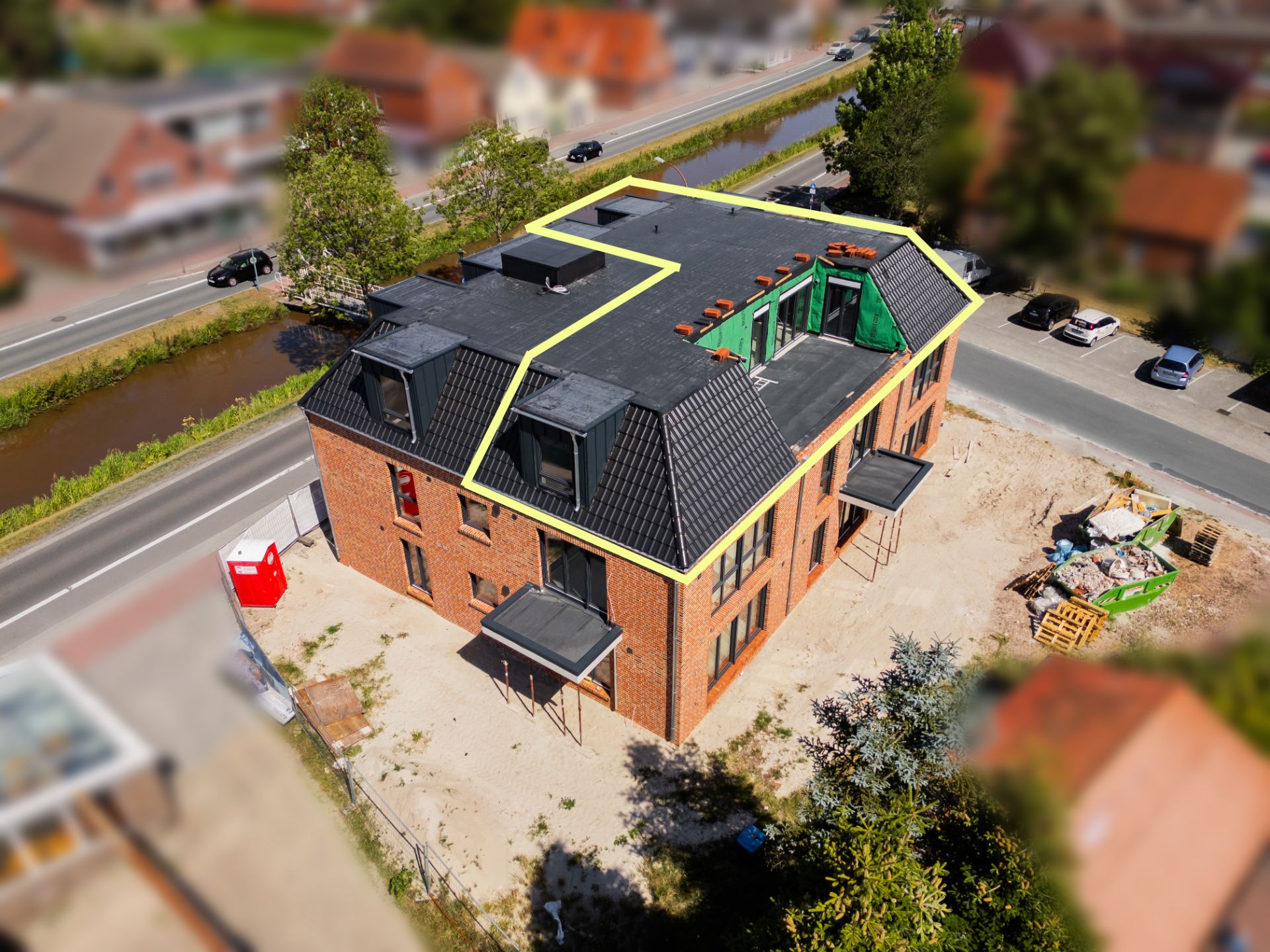 Rotes Backsteinhaus mit schwarzem Dach, Baustelle außen und Straßen rundherum.