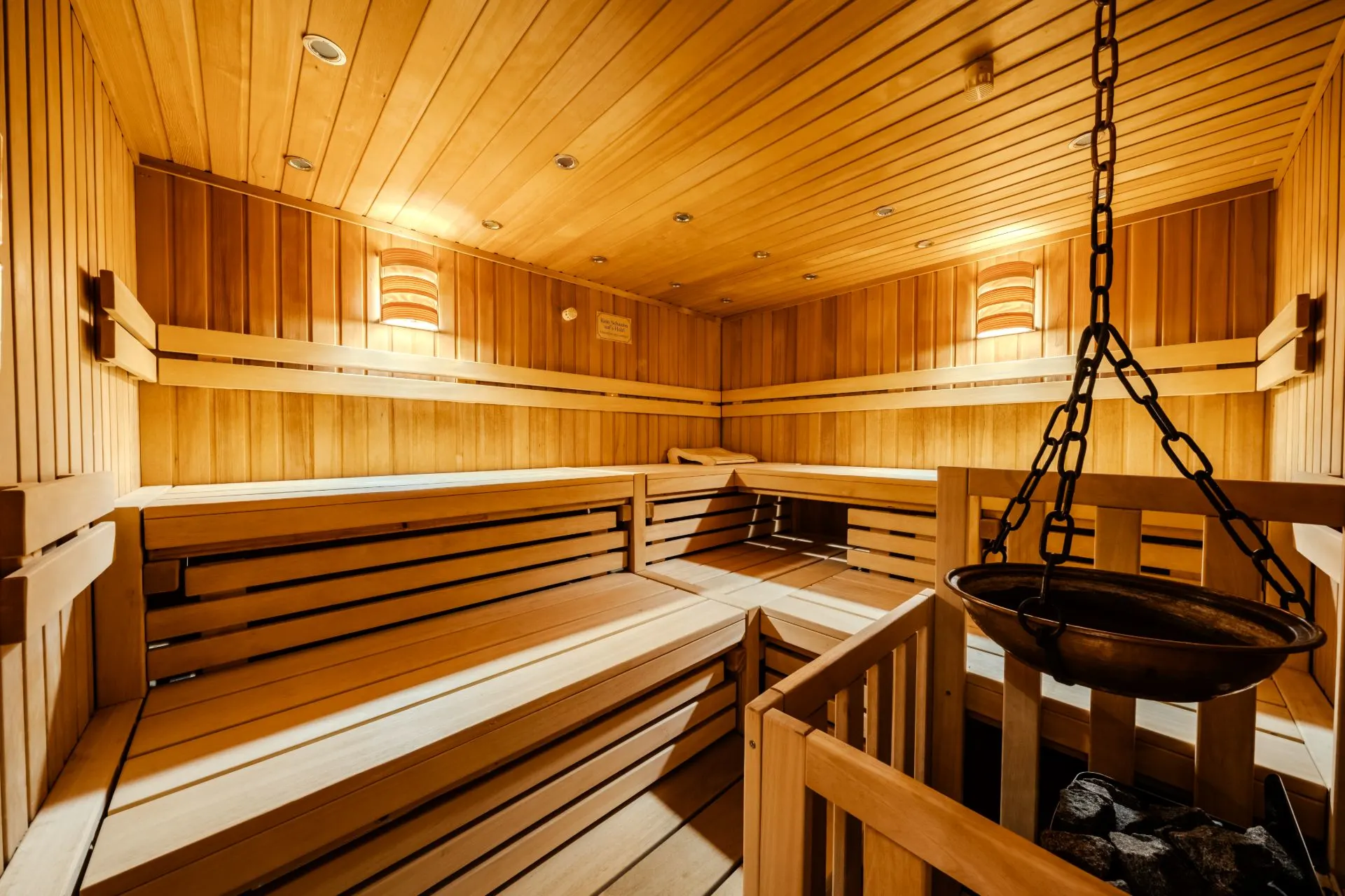 Innenansicht einer modernen Holzsauna mit Bänken und einem Saunaofen.