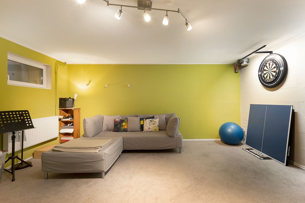 Wohnraum mit Sofa, Notenständer, Dartboard, Tischtennisplatte und Gymnastikball.