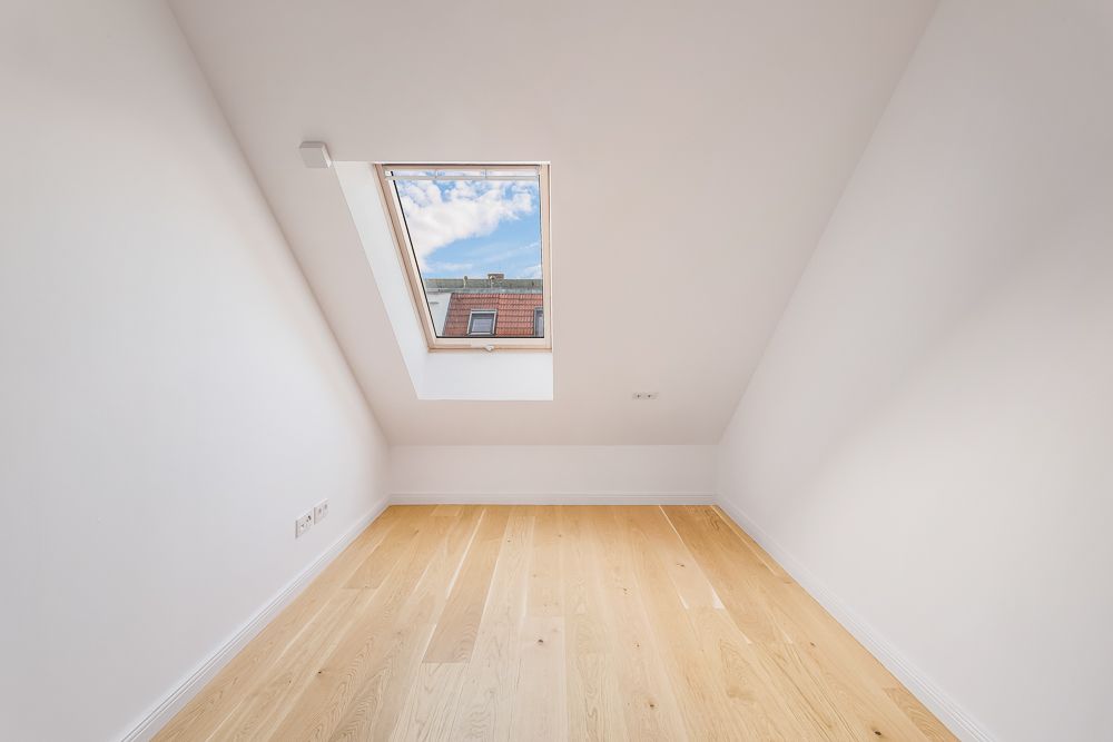 Heller Dachraum mit Holzfußboden und Dachfenster.