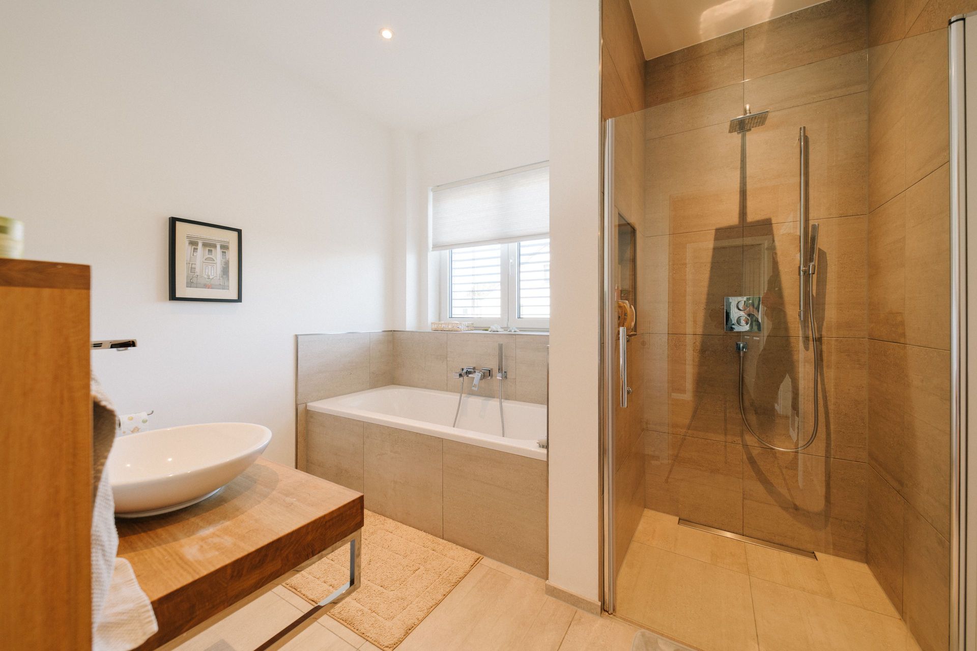 Modernes Badezimmer mit Badewanne, Glasdusche und Waschbecken auf Holzablage.