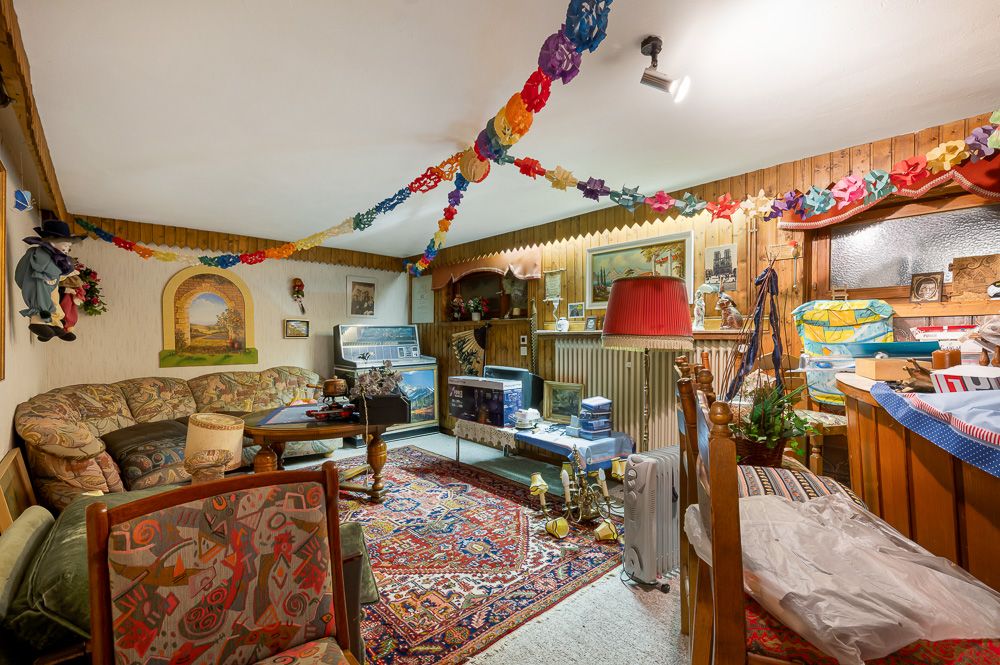 Wohnzimmer mit Teppich, Sofas, Holzvertäfelung und bunter Papiergirlande an der Decke.
