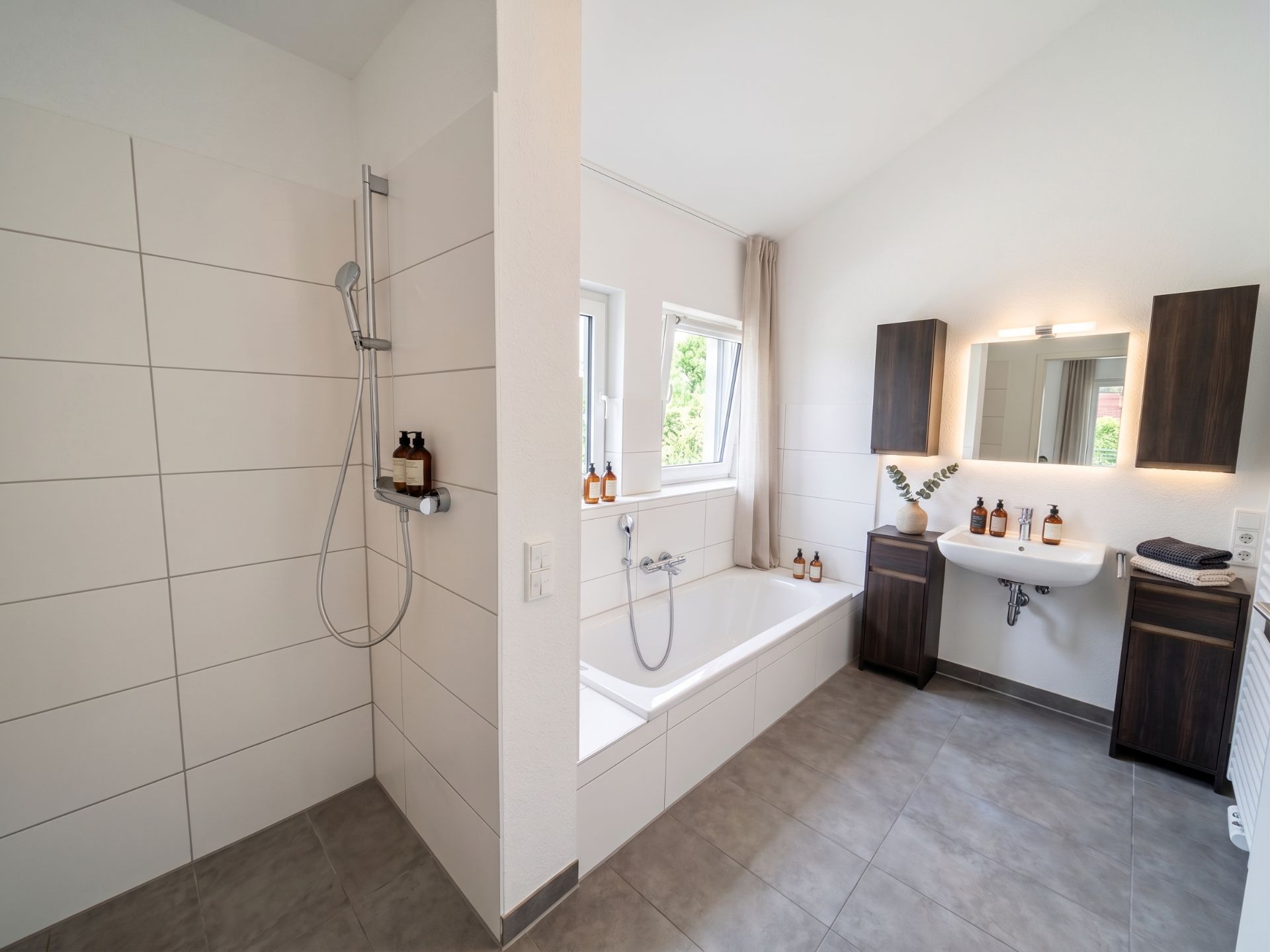 Modernes Badezimmer mit Dusche, Badewanne, Waschbecken und großem Spiegel.