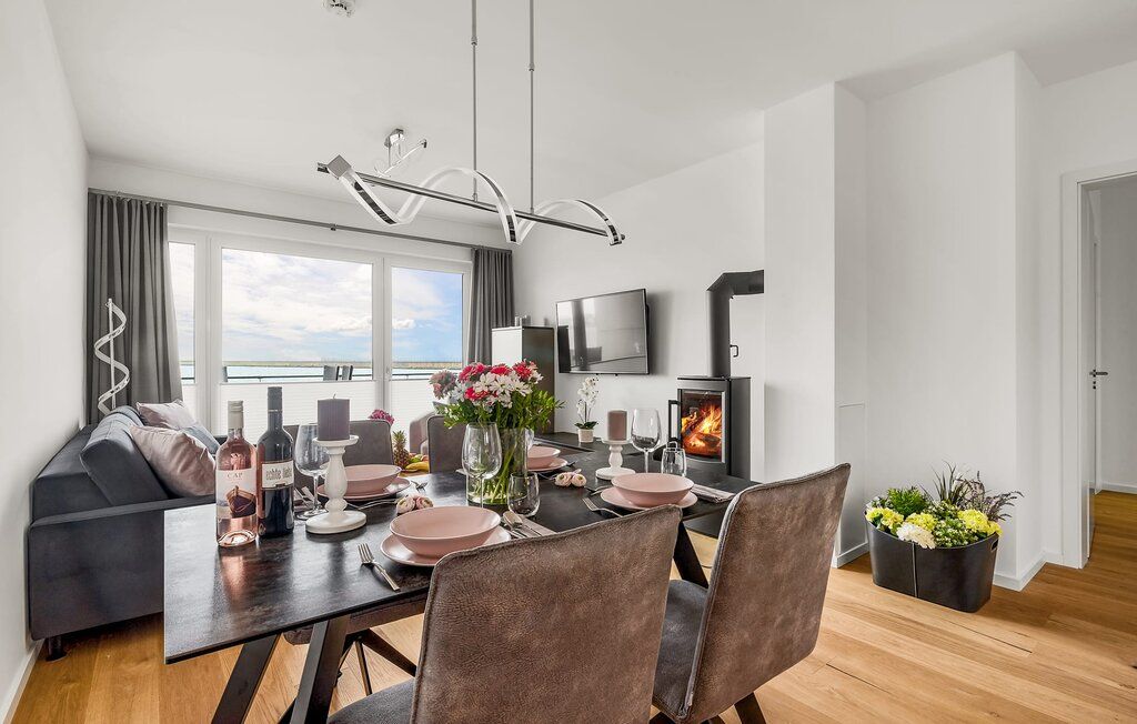 Modernes Wohnzimmer mit Esstisch, Sofa, Kamin, großen Fenstern und Meerblick.