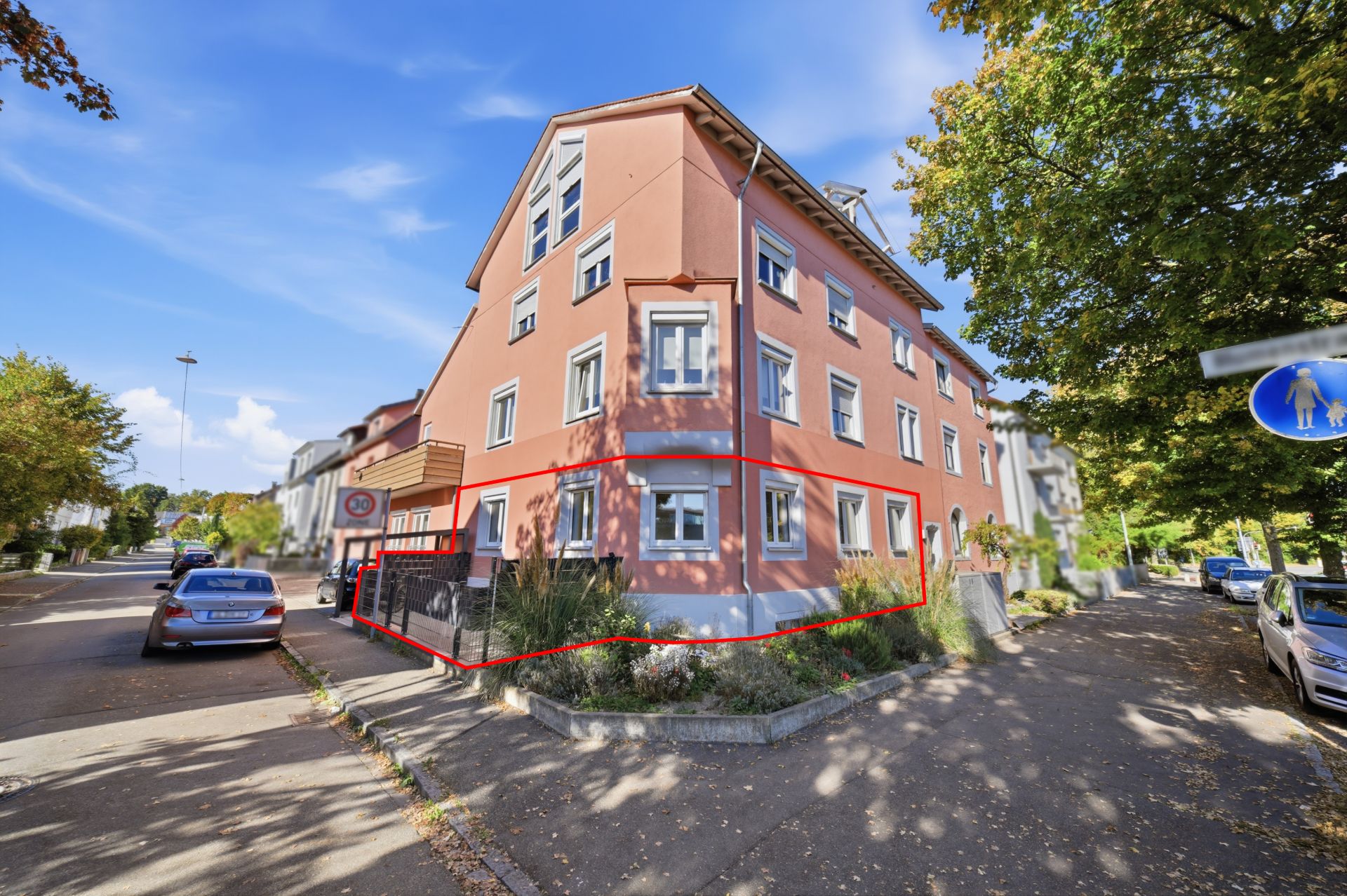 Dreistöckiges Wohnhaus mit rosa Fassade und mehreren Fenstern an einer Straßenecke.