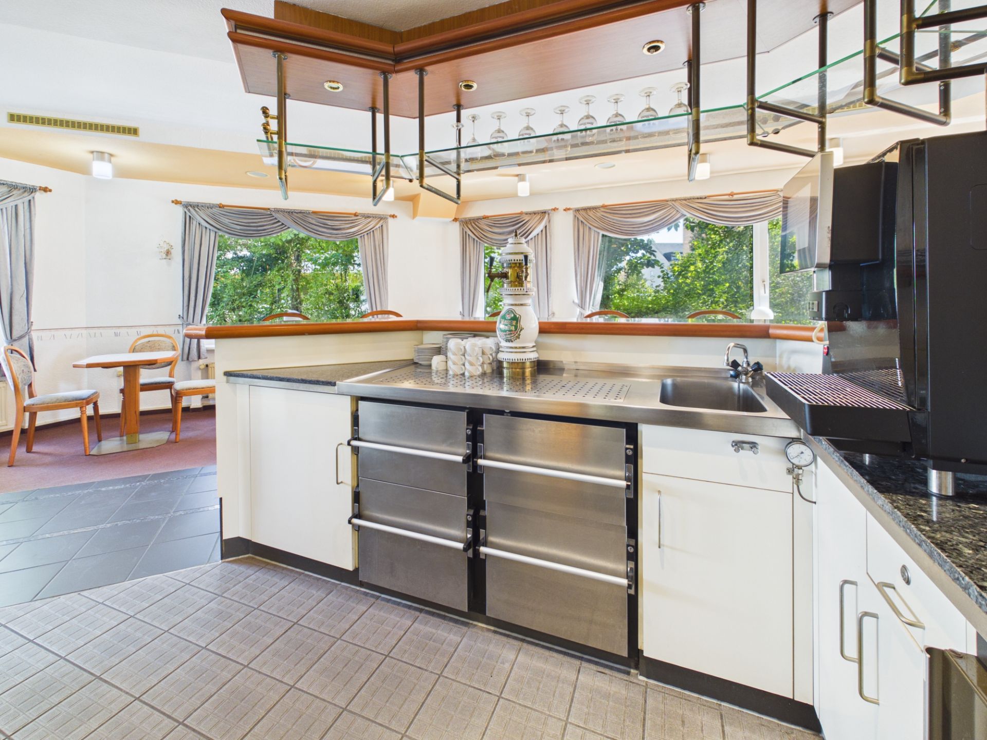 Moderne Küche mit Theke, Edelstahlgeräten und großen Fenstern mit Blick ins Grüne.