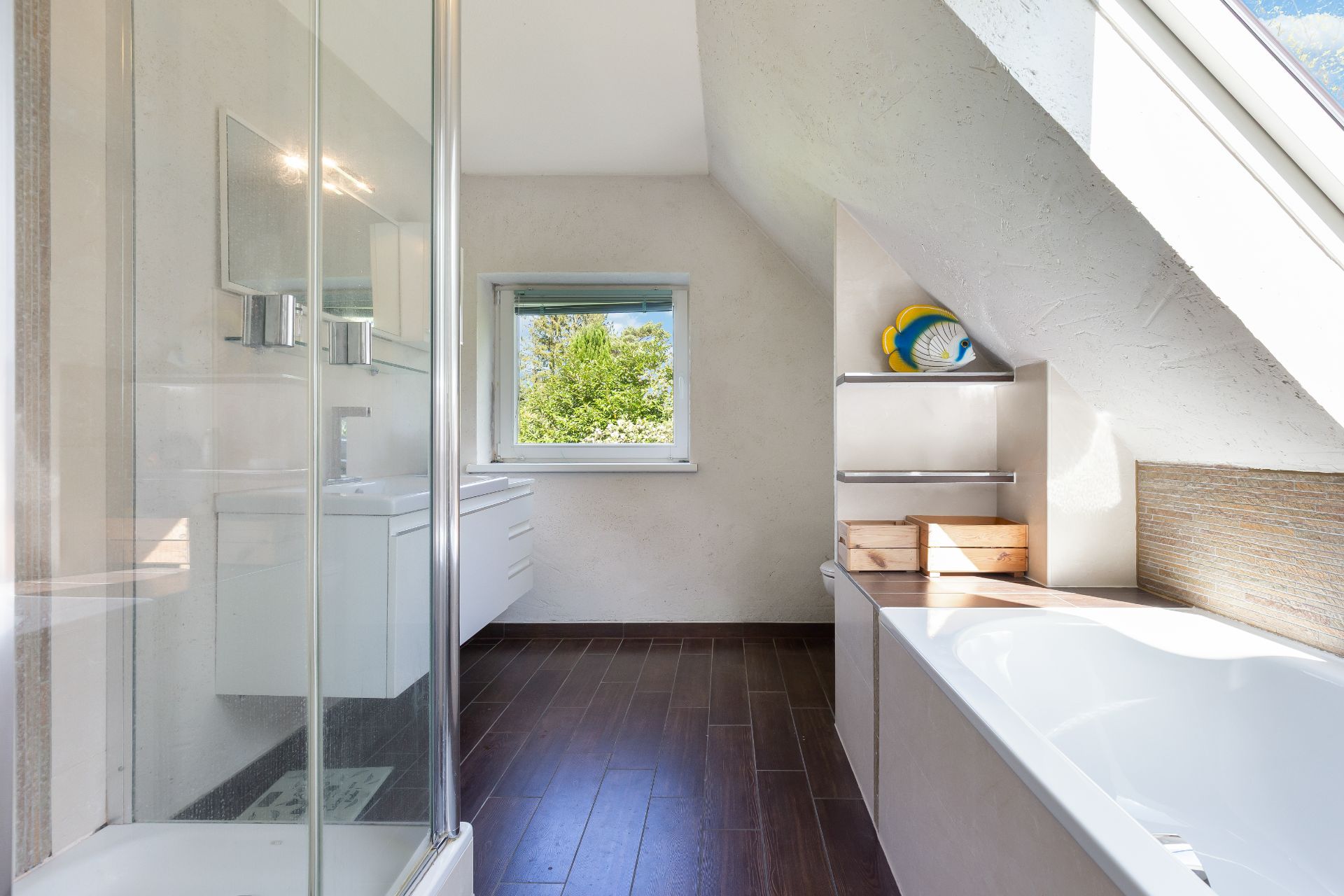 Modernes Badezimmer mit Dusche, Badewanne und Fenster mit Blick ins Grüne.