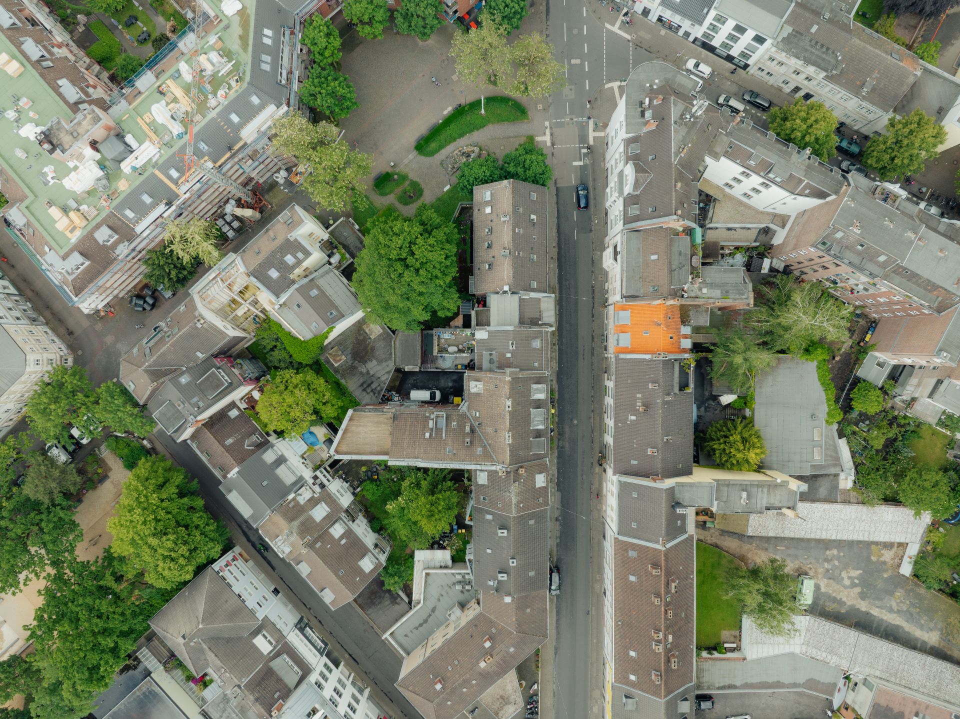 Luftaufnahme von Wohnhäusern, einer Straße und Bäumen in einem städtischen Wohngebiet.