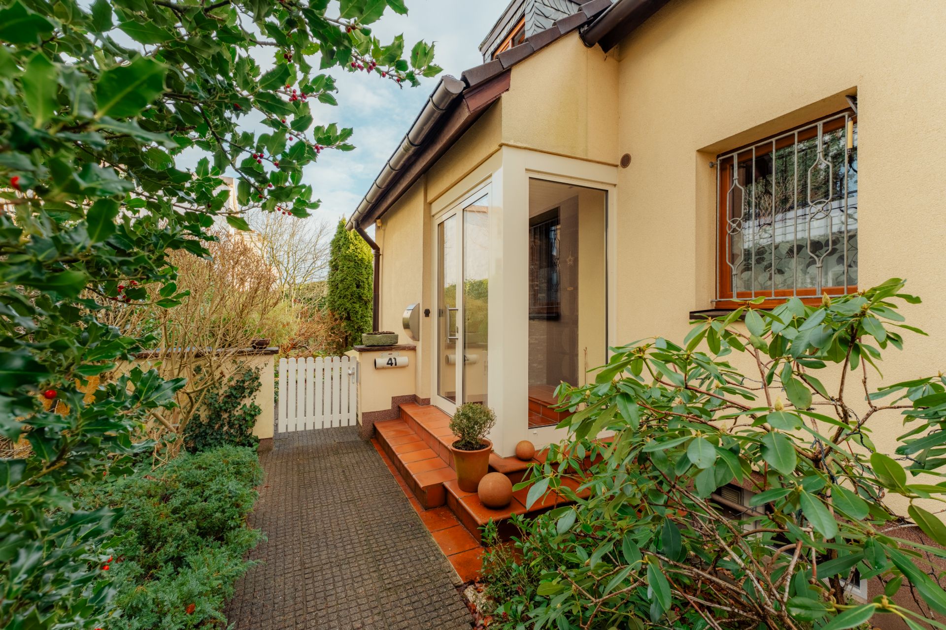 Eingangsbereich eines Wohnhauses mit Treppe, Pflanzen und Glastür.
