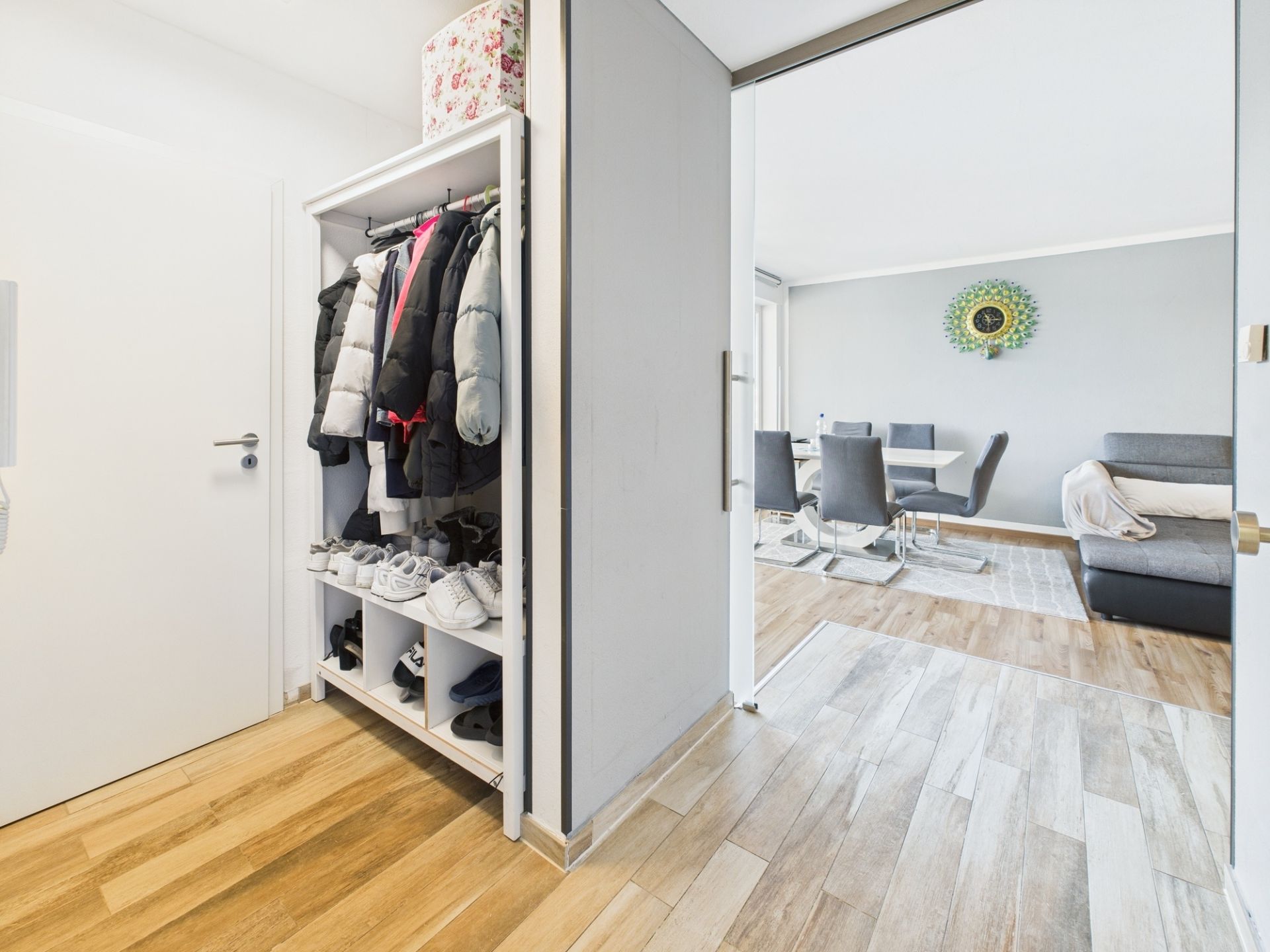 Flur mit Garderobe, Blick ins Wohnzimmer mit Esstisch, Stühlen und Sofa.