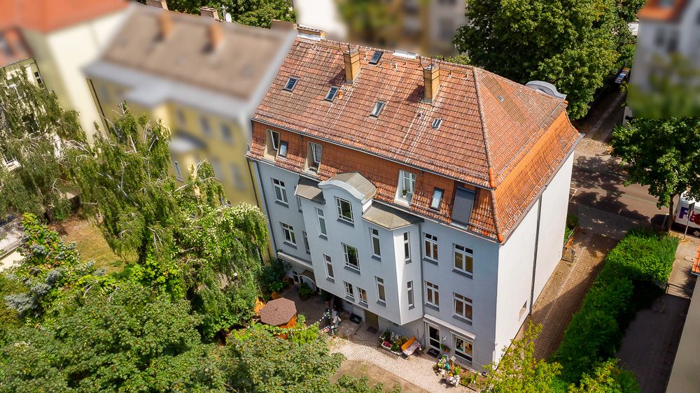 Mehrstöckiges Wohnhaus mit rotem Dach und Garten, aus der Vogelperspektive aufgenommen.
