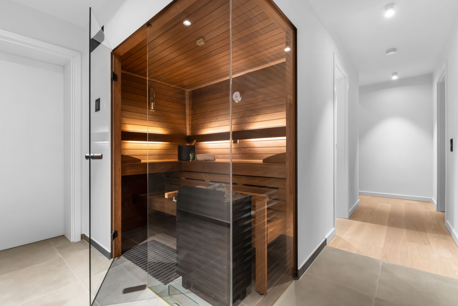 Moderne Sauna mit Glasfront in einem hellen Flur eines Wohnhauses.