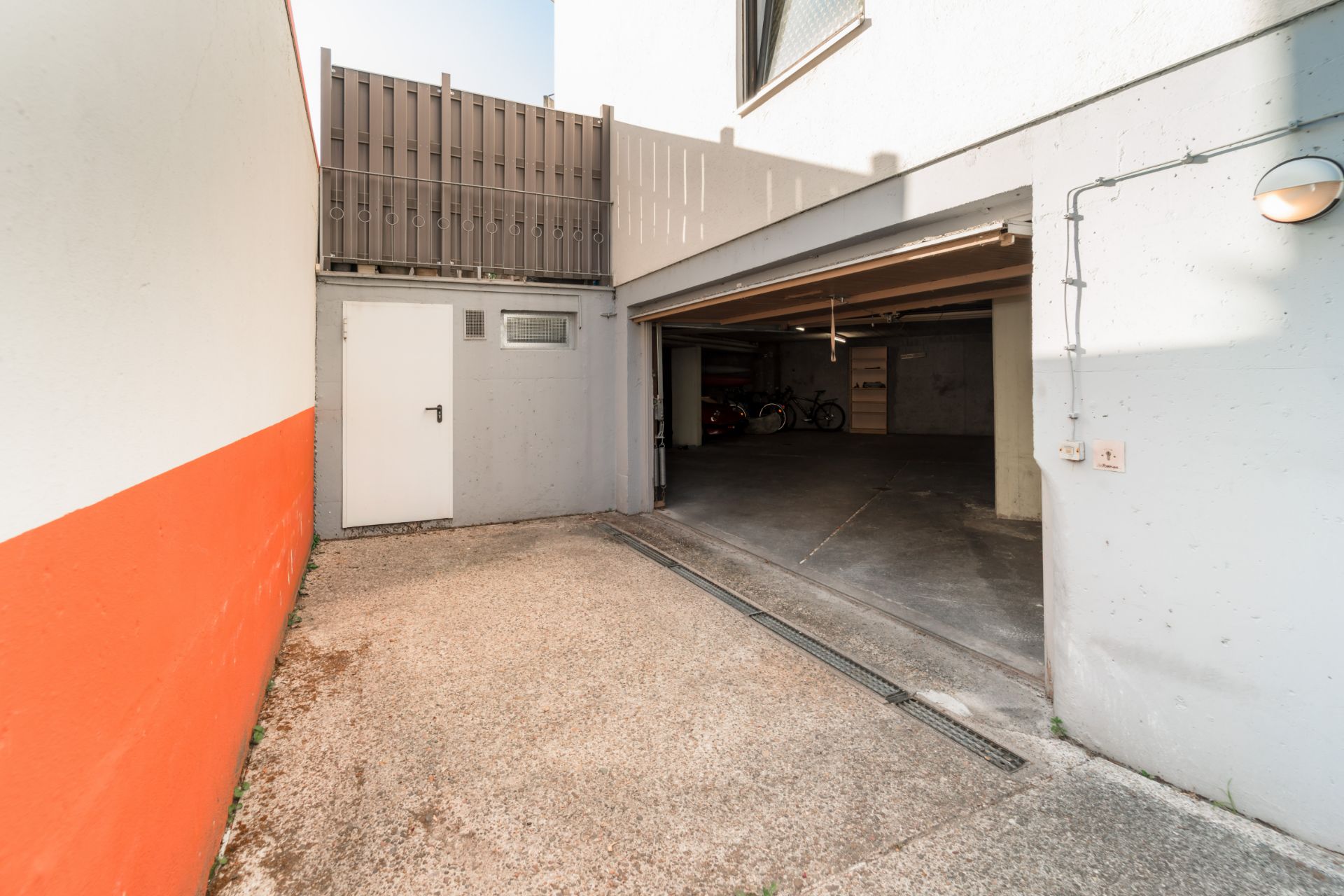 Offene Garage mit zwei Fahrrädern im Hintergrund und Tür an der linken Wand.