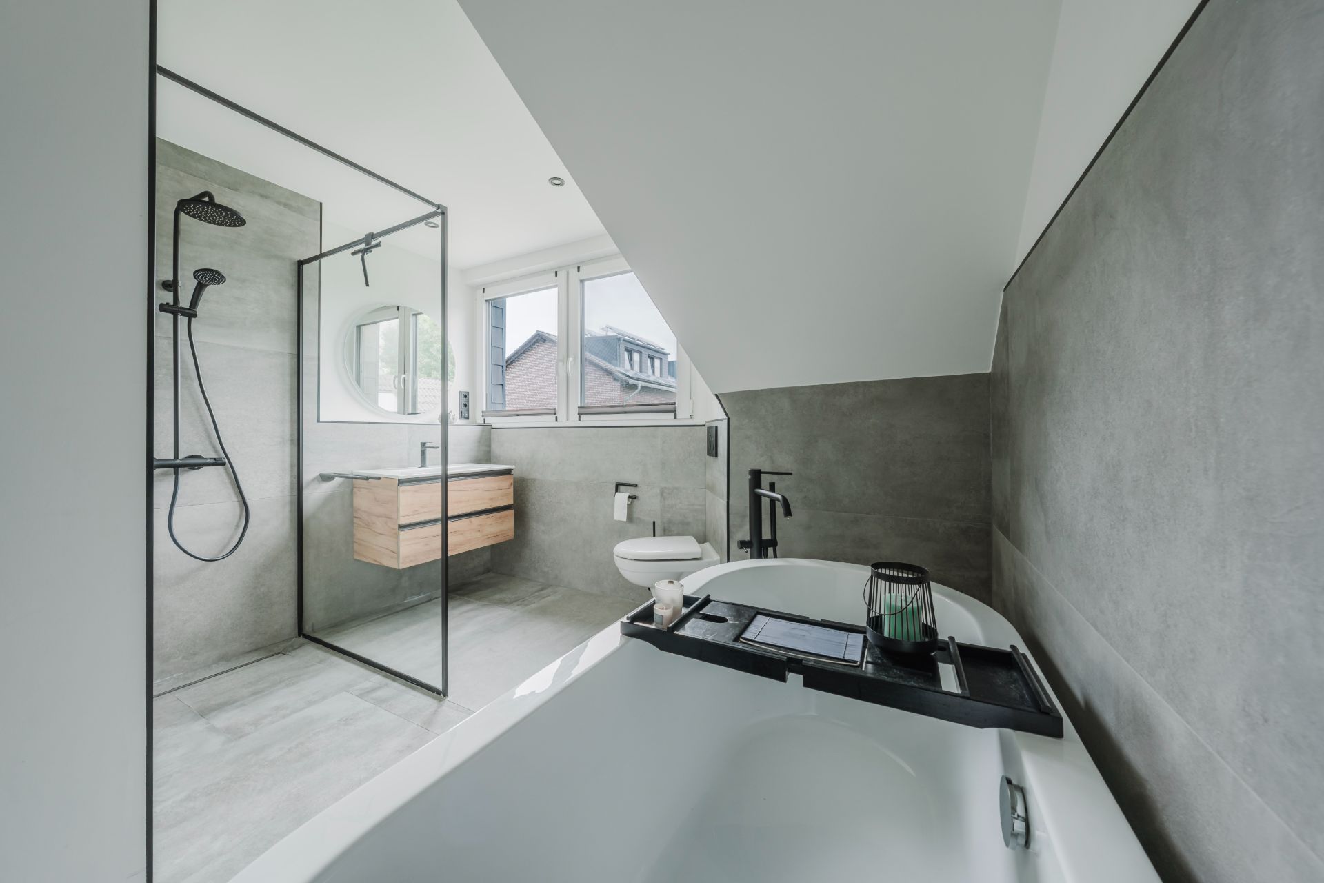 Modernes Badezimmer mit freistehender Badewanne, Dusche, WC und Waschbecken unter Dachschräge.