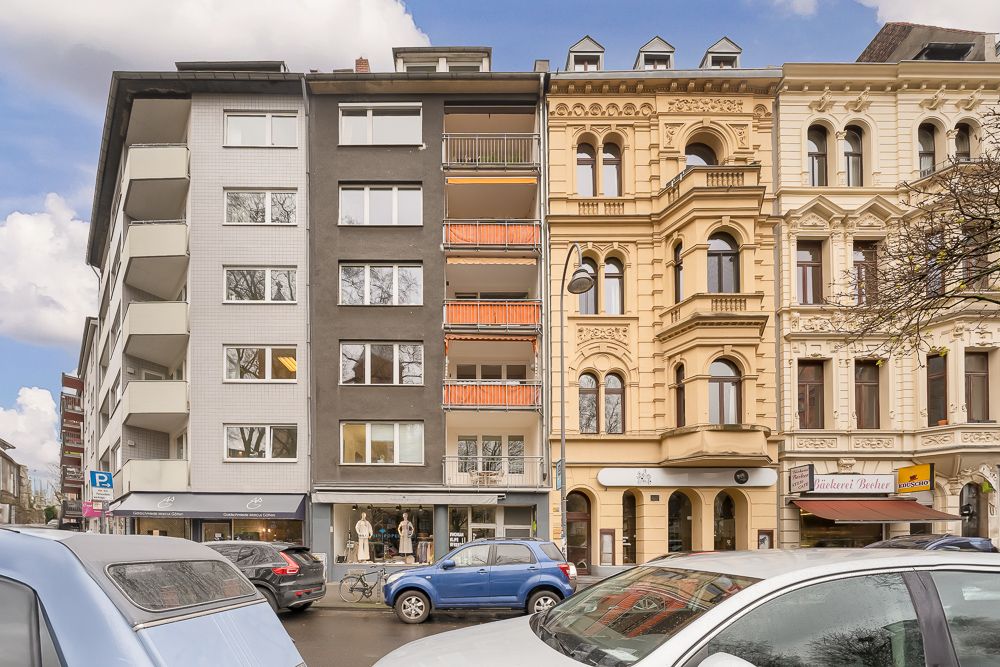 Mehrgeschossige Wohnhäuser mit Balkonen und geparkten Autos davor.