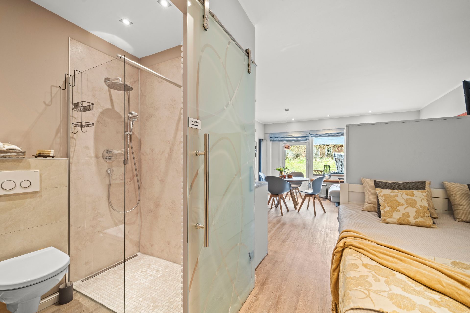 Modernes Bad mit Dusche neben offenem Wohn- und Essbereich mit Sofa und Esstisch.