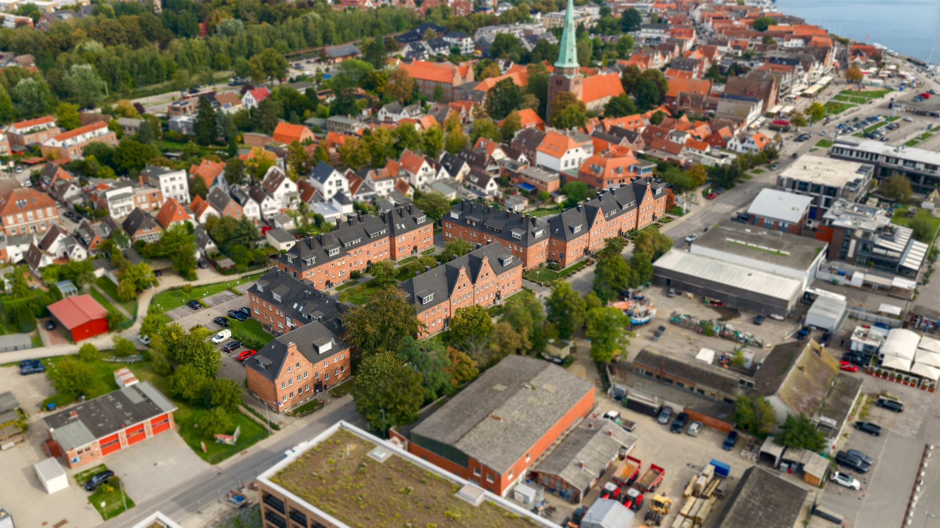 Luftaufnahme eines Wohngebiets mit roten Häusern, Bäumen und Straßen.