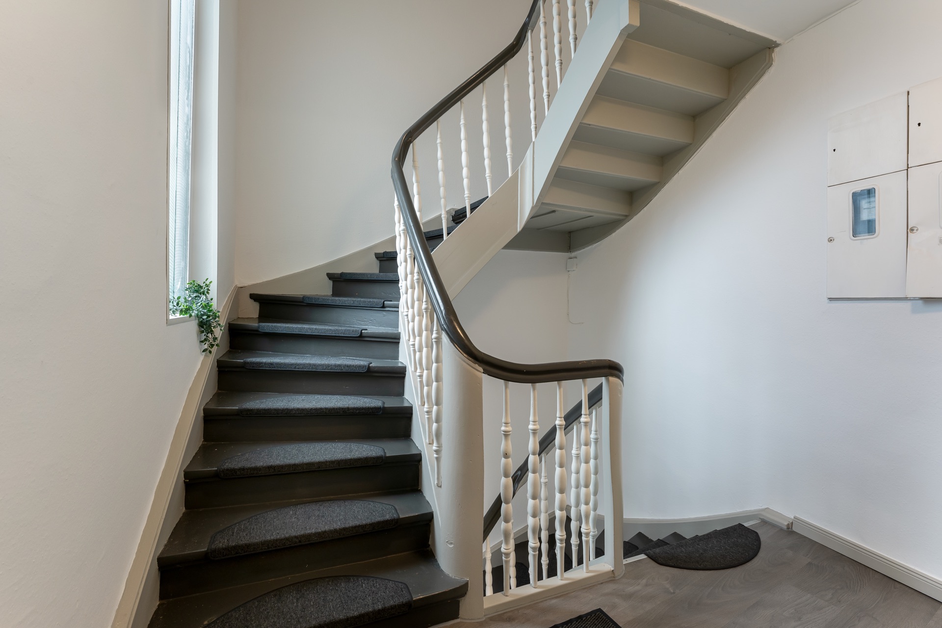 Innenansicht eines Treppenhauses mit grauer Treppe und weißem Geländer.