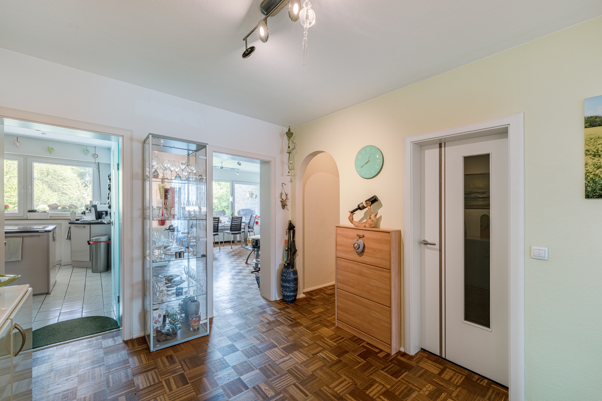 Heller Flur mit Glaskommode, Holzboden und Blick in Küche und Esszimmer.