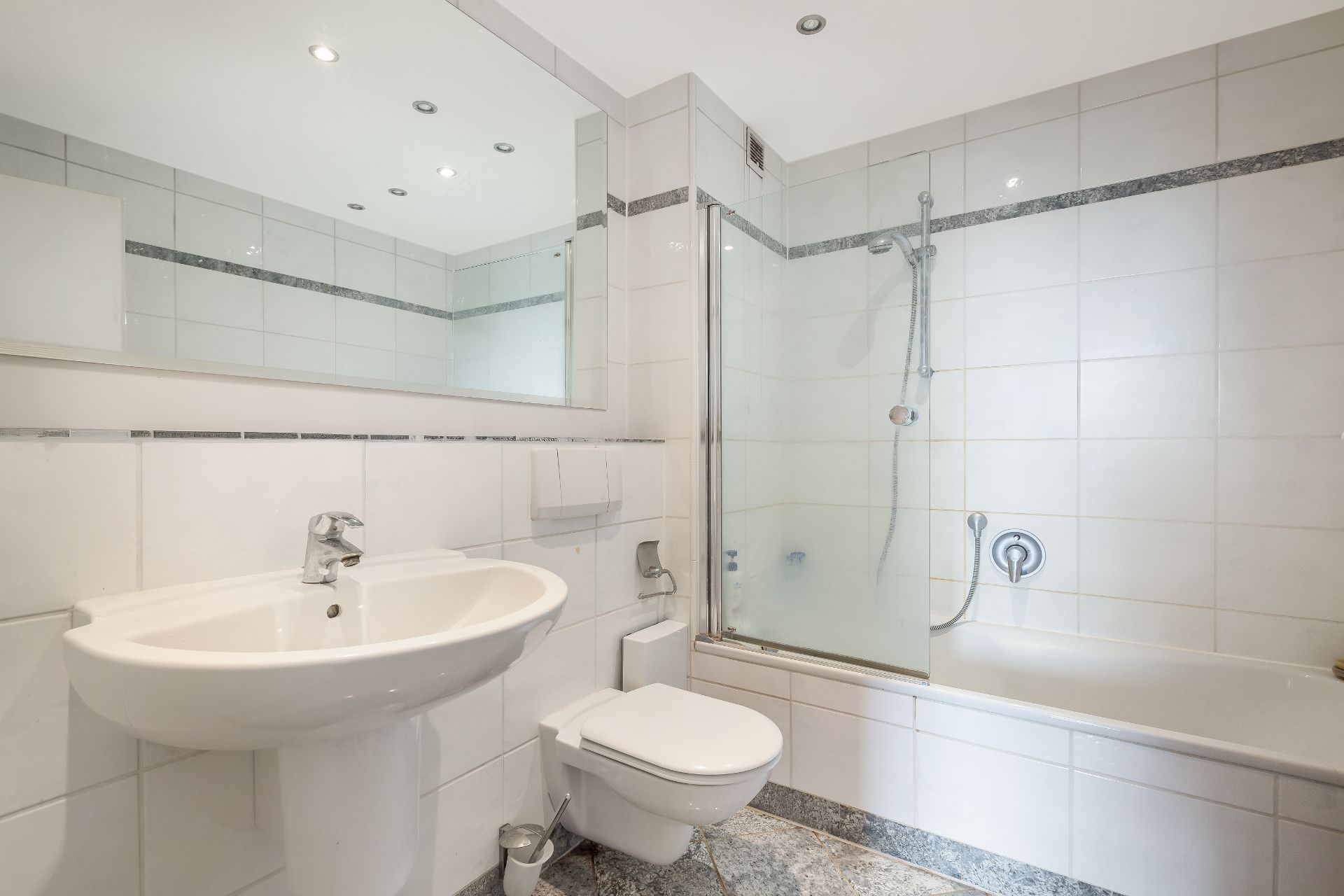 Modernes Badezimmer mit Waschbecken, Toilette, Badewanne und Duschvorrichtung.