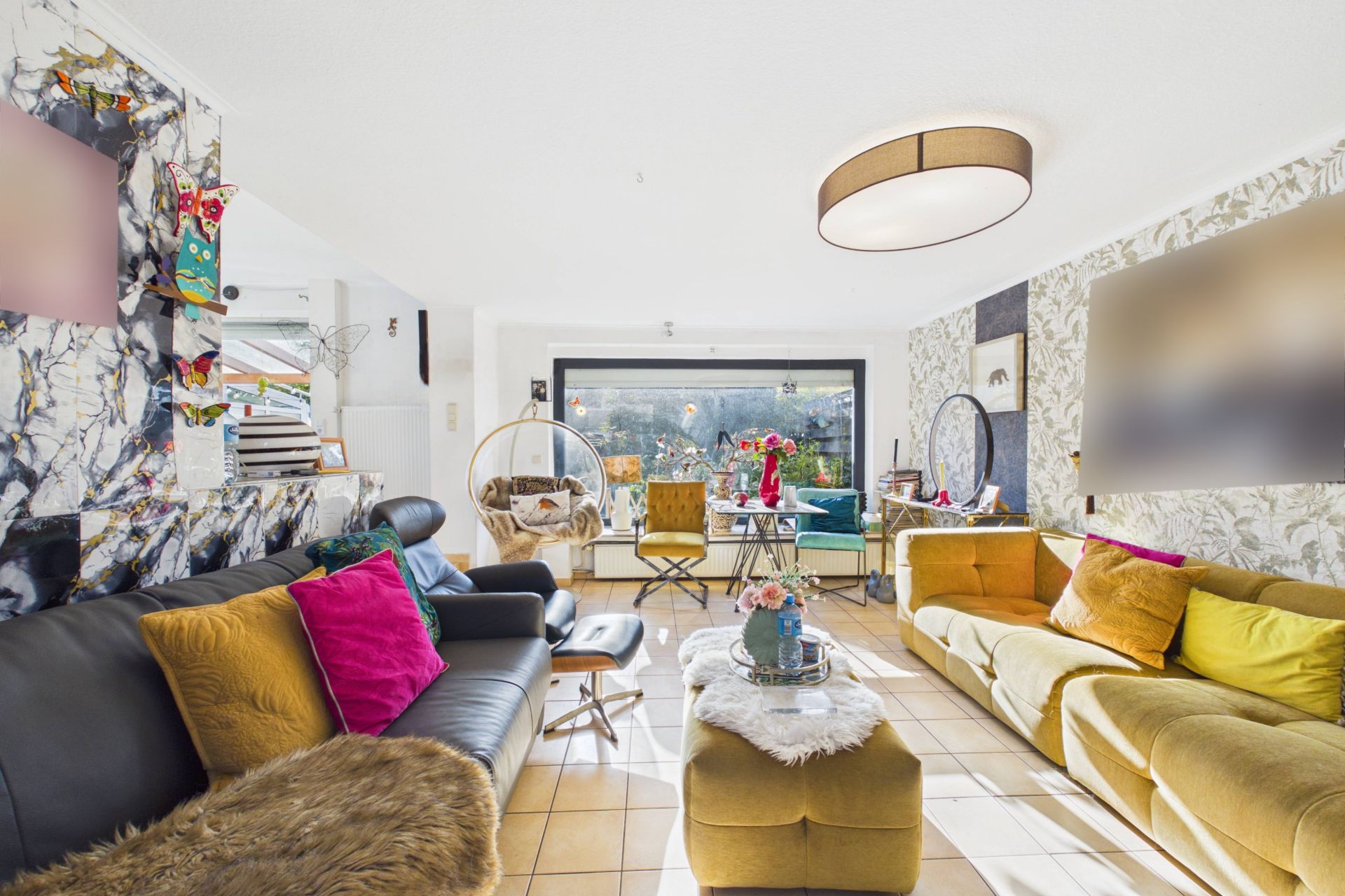 Helles Wohnzimmer mit zwei Sofas, Couchtisch, bunten Kissen und großem Fenster.
