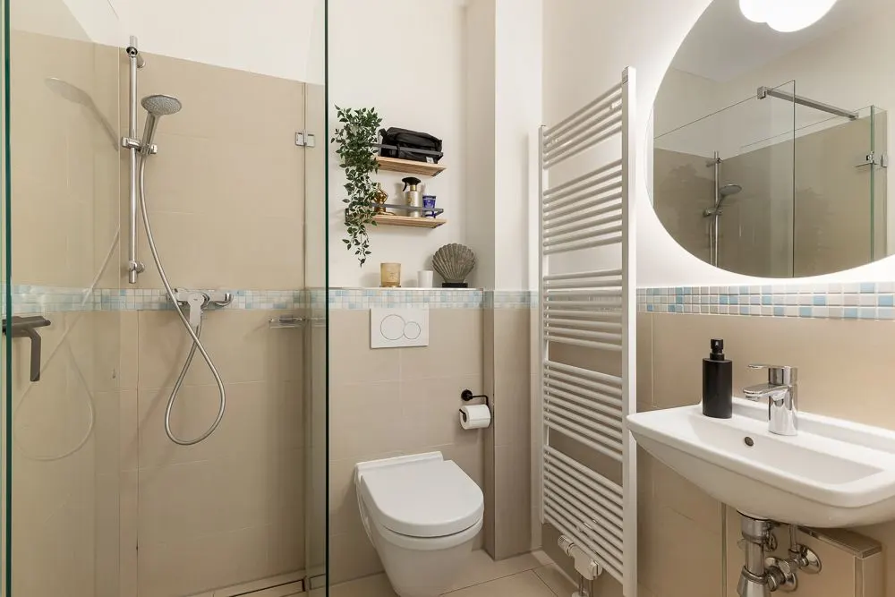 Modernes Badezimmer mit Dusche, Wandtoilette, Waschbecken und Handtuchheizkörper.