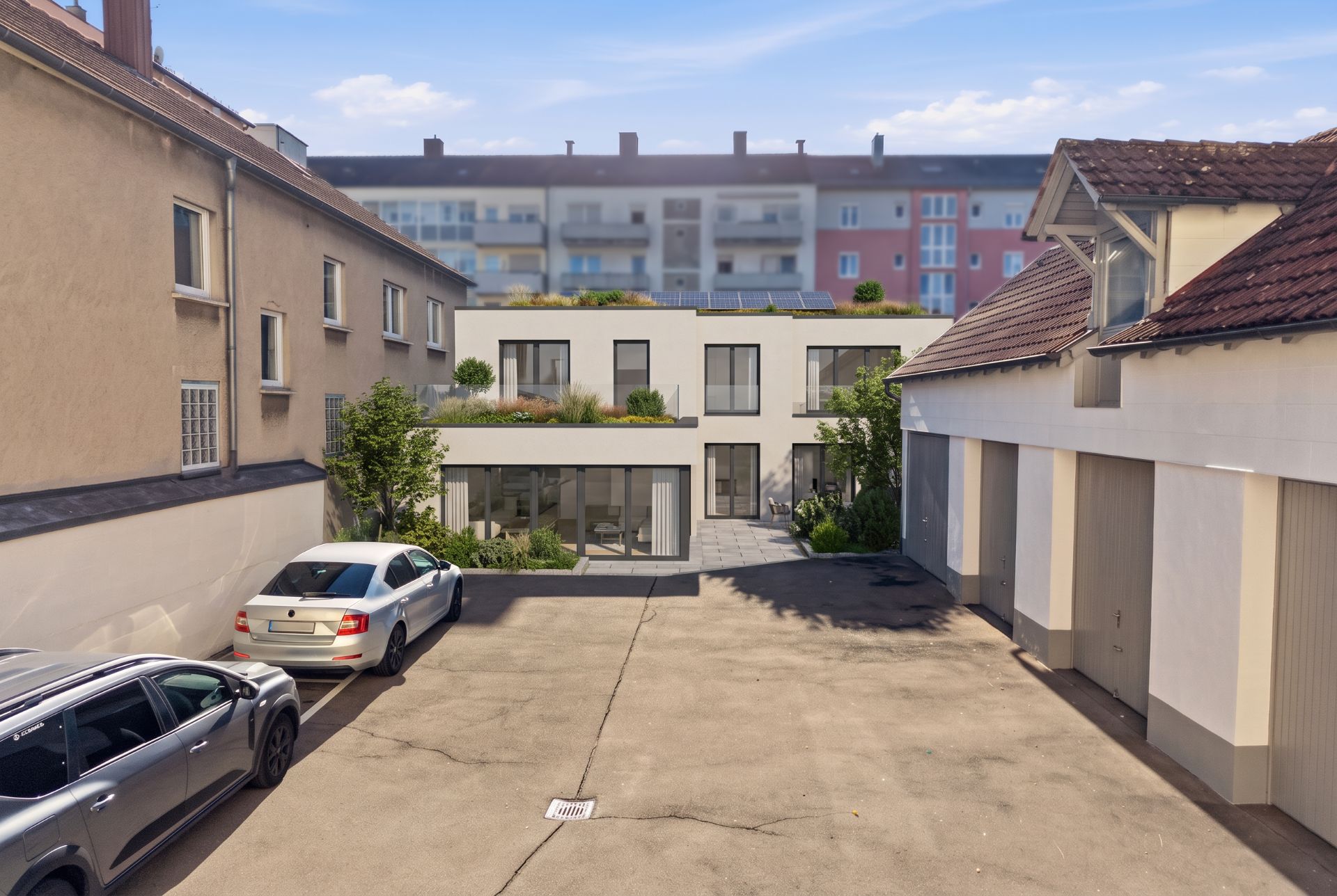 Moderner Innenhof mit geparkten Autos, Garagen und einem zweistöckigen Wohnhaus mit Garten.