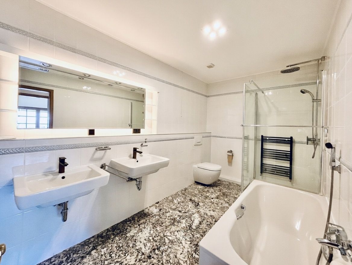 Modernes Badezimmer mit zwei Waschbecken, Badewanne, Dusche und WC, großer Spiegel an der Wand.