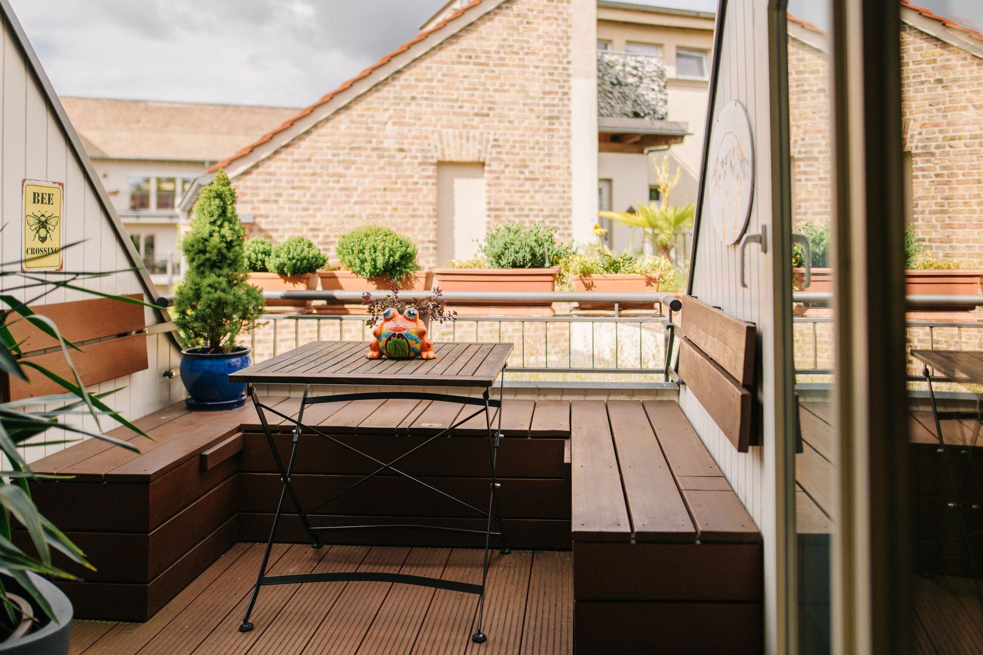 Kleine Terrasse mit Holzbänken, Tisch und Pflanzkübeln im Freien.