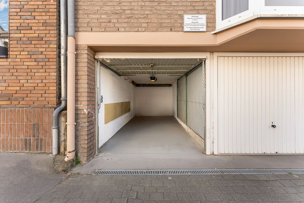 Offene Garage mit Betonboden und Decke, seitlichen Wänden und Licht an der Decke.