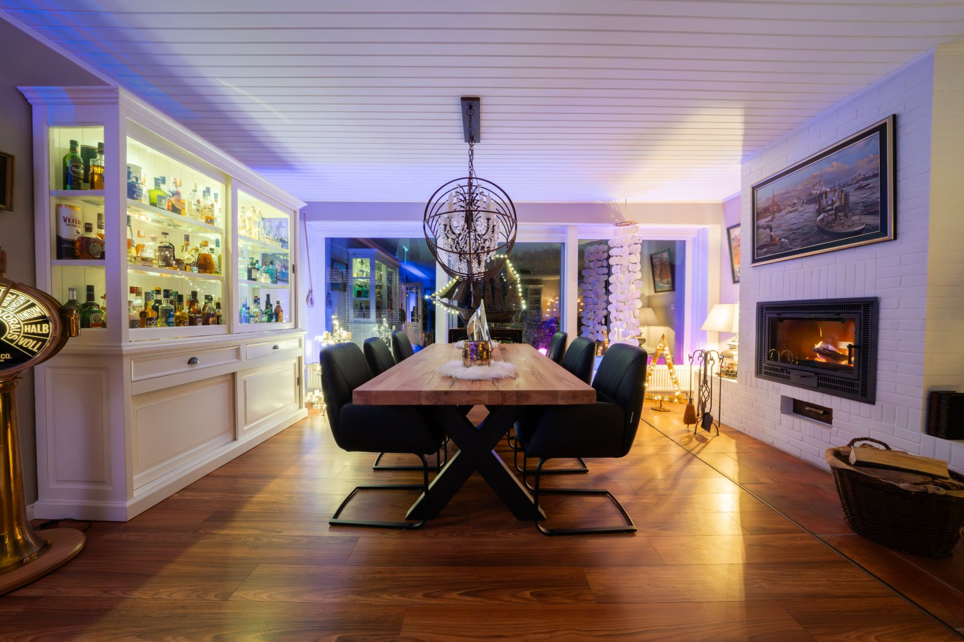 Modernes Esszimmer mit Holztisch, schwarzen Stühlen, Kamin und beleuchtetem Regal.