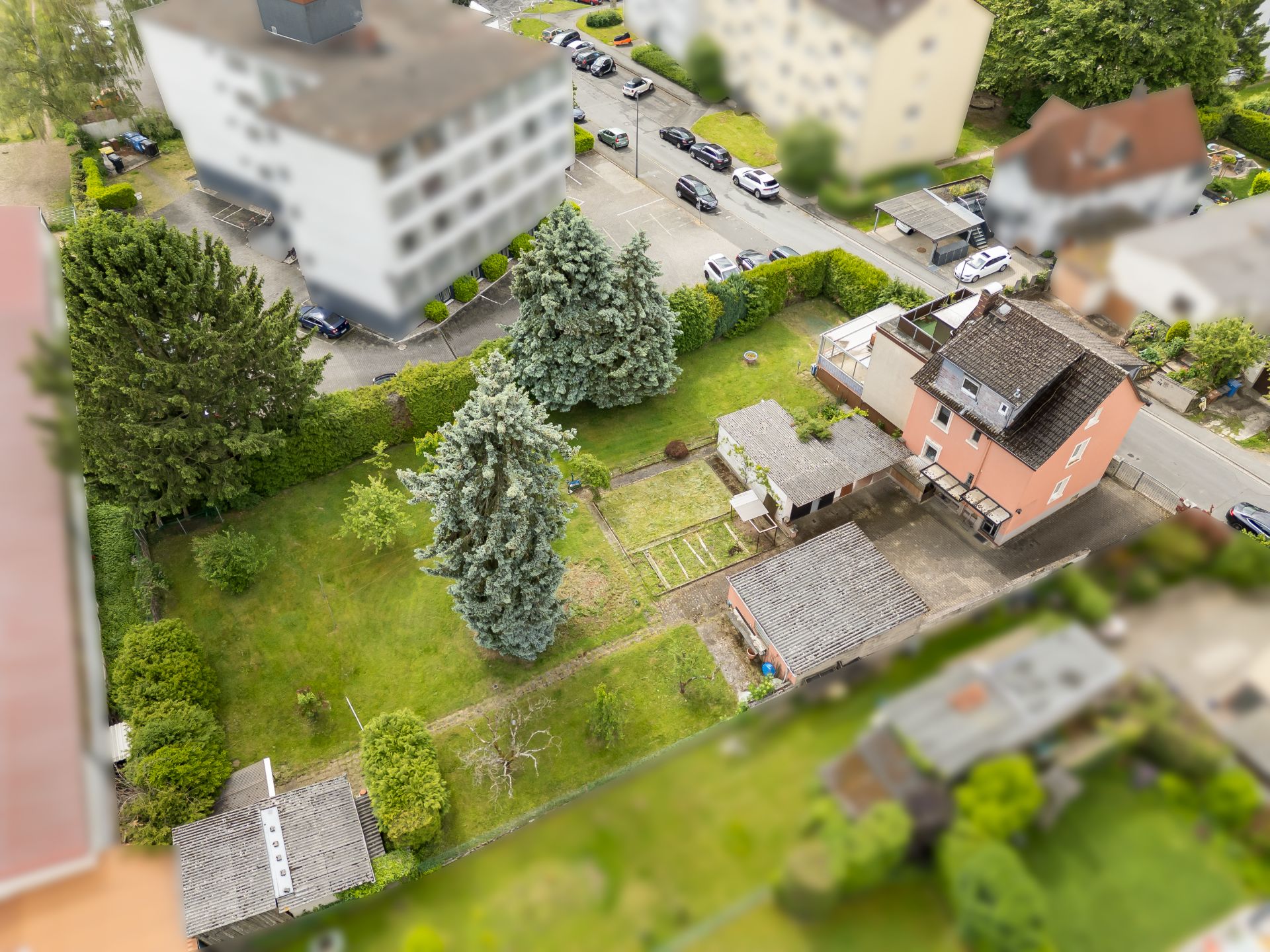 Luftaufnahme eines Hauses mit großem Garten, mehreren Bäumen und Nebengebäuden.
