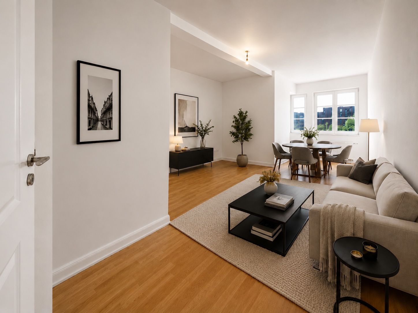Helles Wohnzimmer mit Sofa, Couchtisch, Esstisch, großen Fenstern und Holzboden.