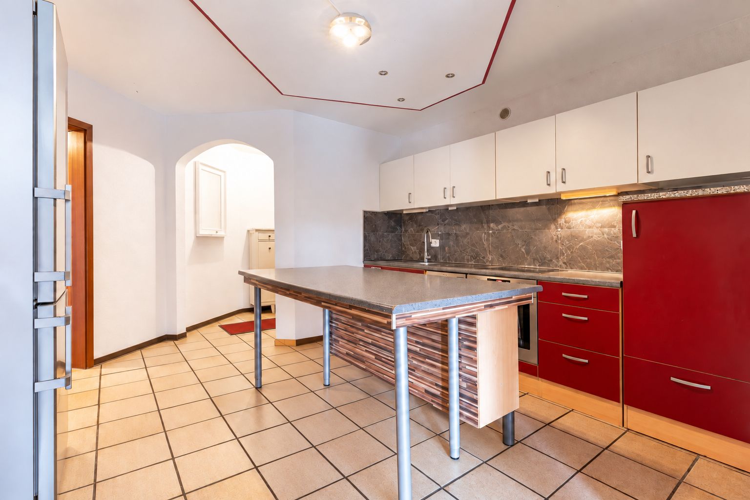 Moderne Küche mit rotem Schrank, Kochinsel und weißen Oberschränken.