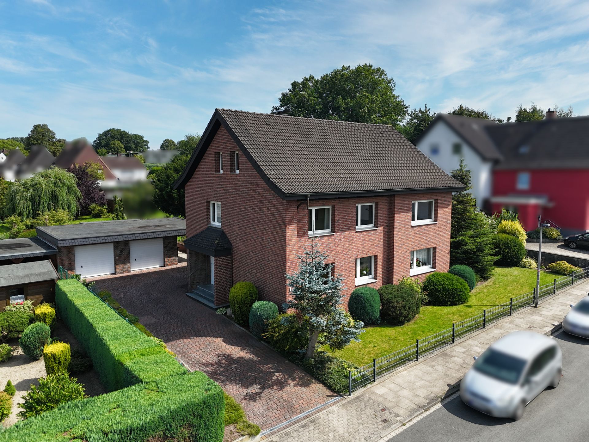 Backsteinhaus mit Vorgarten, Einfahrt und Garage, an einer ruhigen Wohnstraße.
