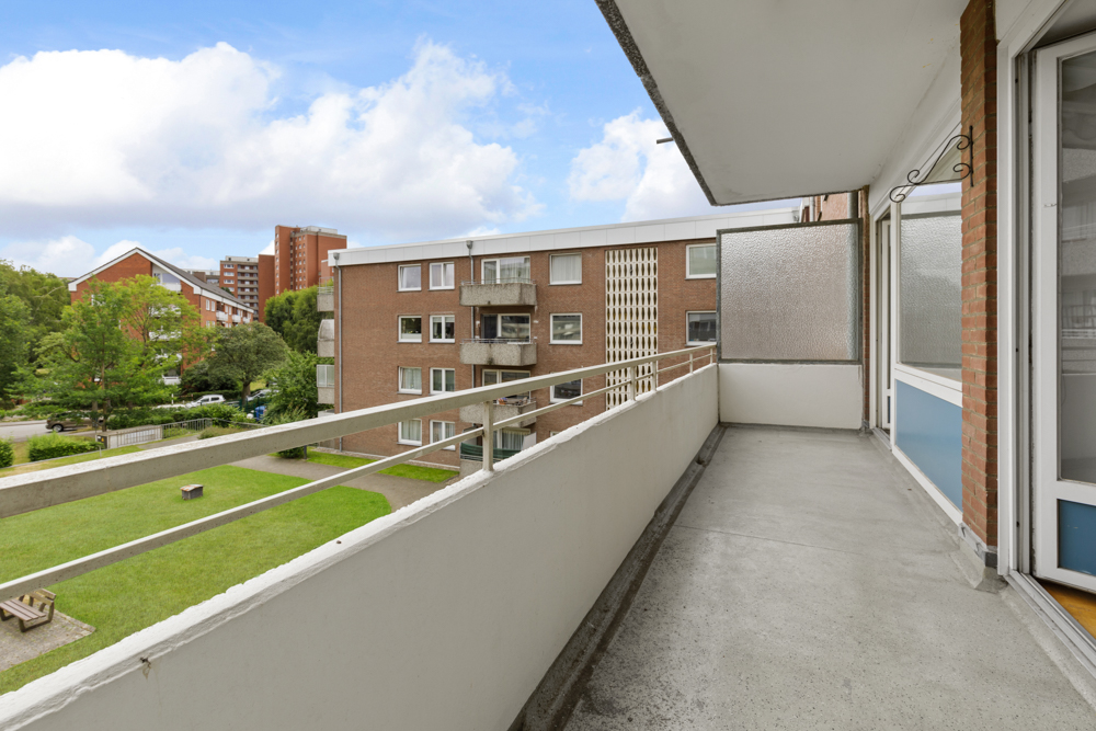 Balkon mit Blick auf grünen Innenhof und umliegende Wohngebäude.