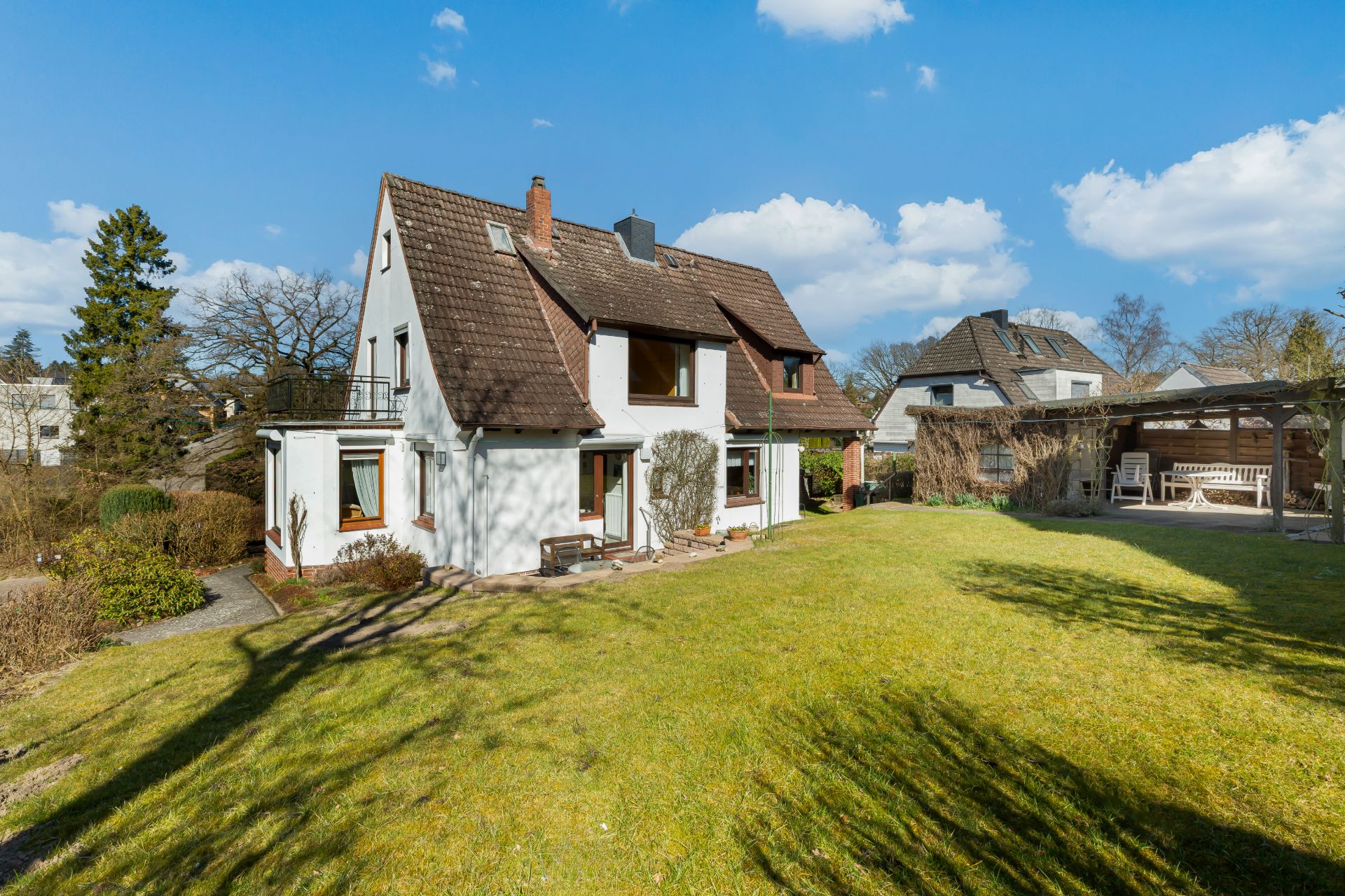 Zweistöckiges Haus mit Satteldach und großem Garten bei sonnigem Wetter.