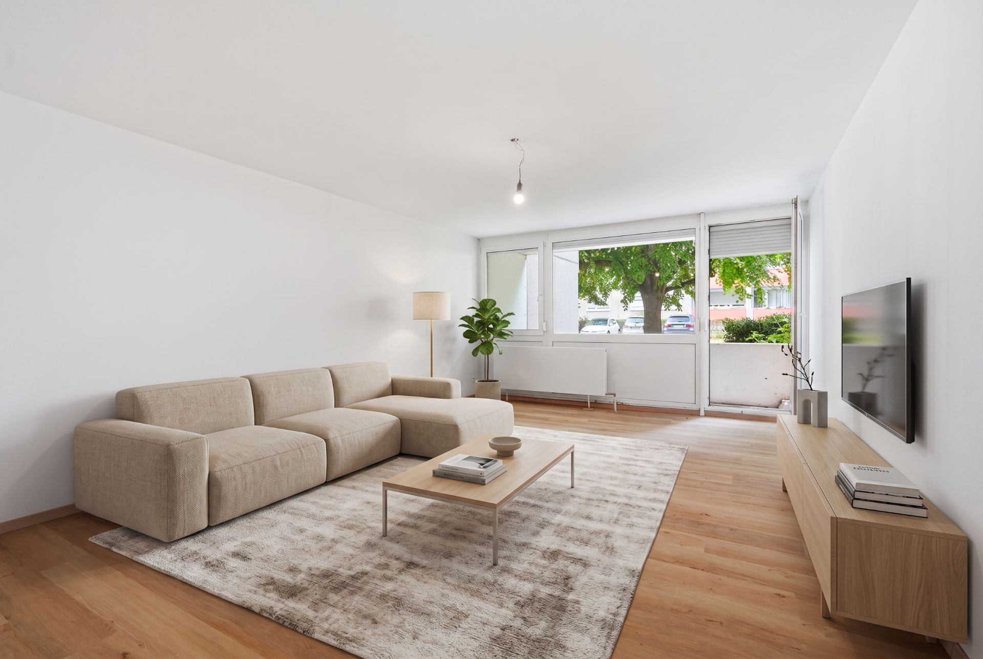 Helles Wohnzimmer mit beigem Sofa, Teppich, Couchtisch und großem Fenster zum Garten.