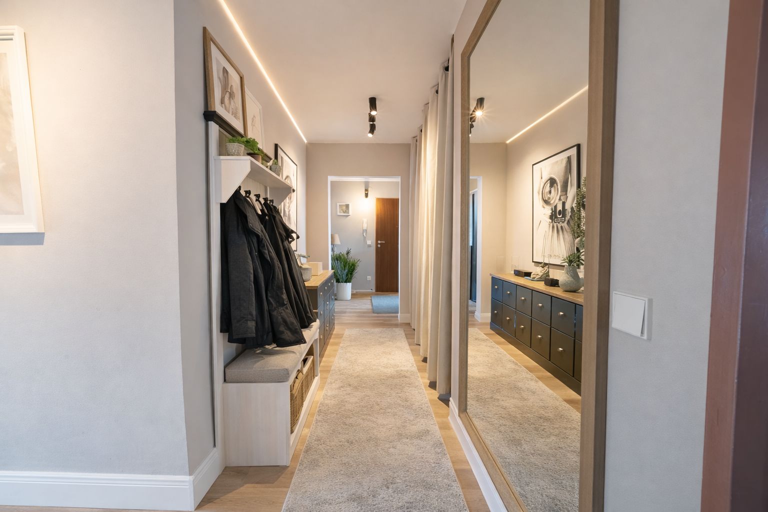Heller Flur mit Spiegel, Garderobe, Teppich und Kommode in einer Wohnung.