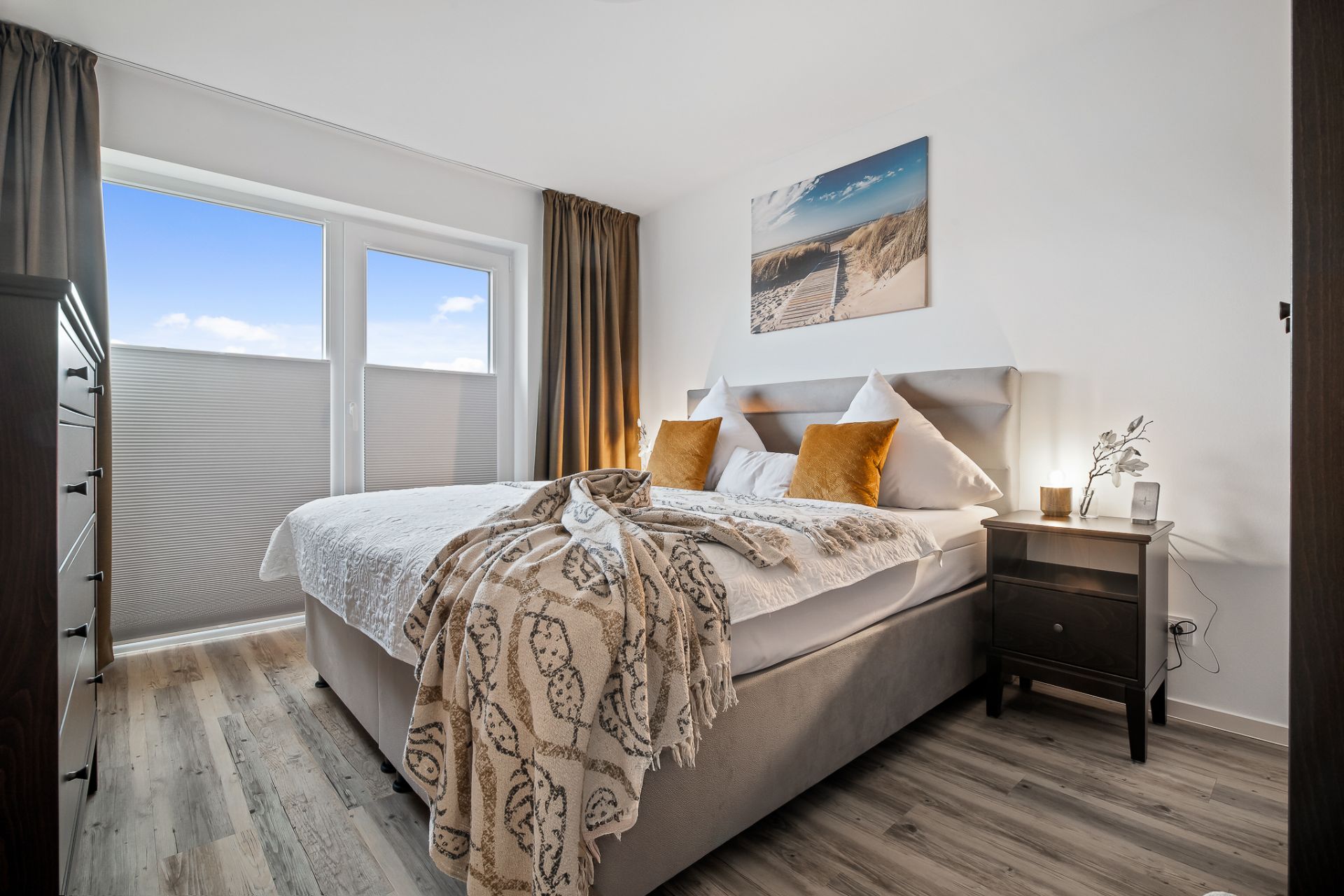 Modernes Schlafzimmer mit großem Bett, Nachttischen und Fenster mit Vorhängen.