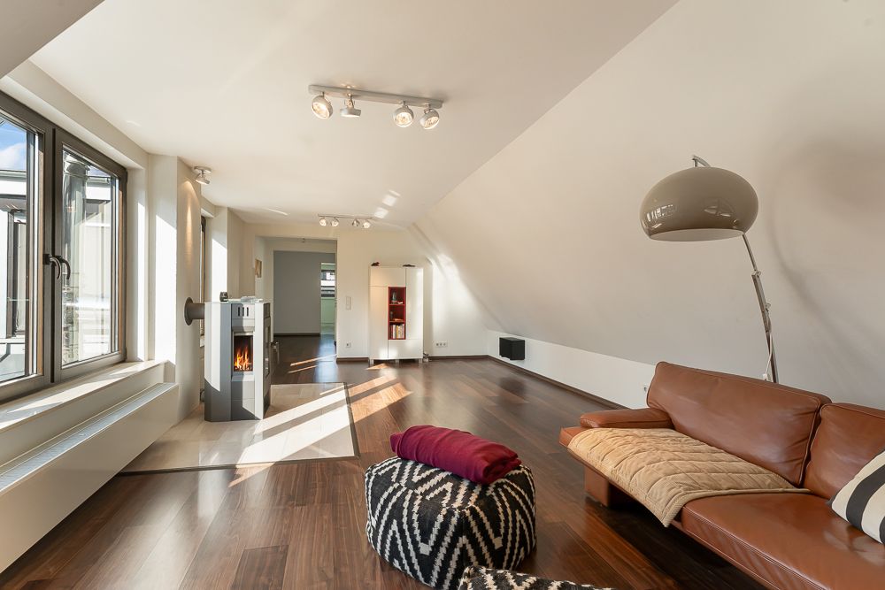 Modernes Wohnzimmer mit braunem Sofa, Kamin, großen Fenstern und Holzboden.