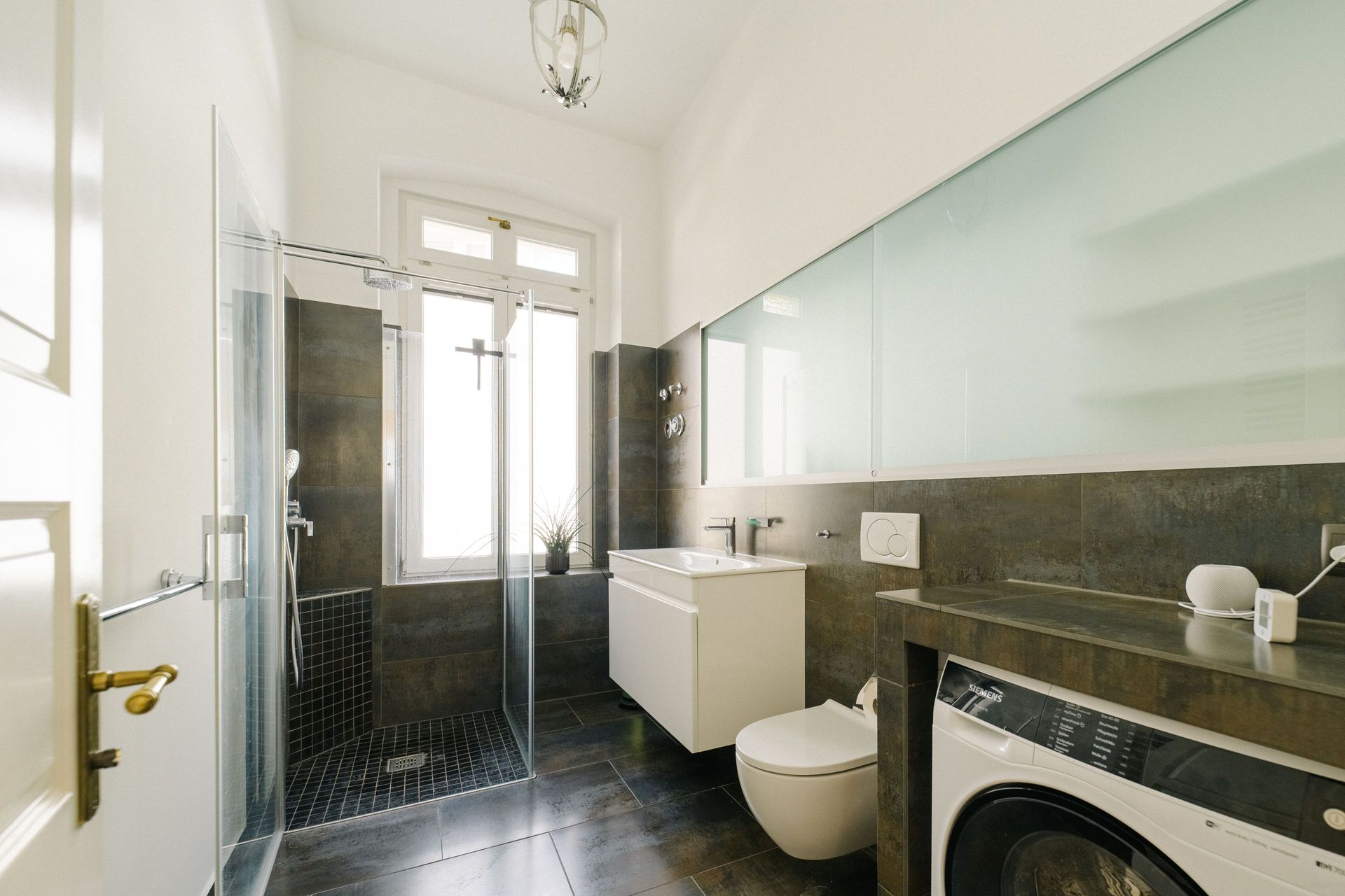 Modernes Badezimmer mit begehbarer Dusche, Waschbecken, Toilette und Waschmaschine.